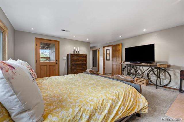 Bedroom with a yellow patterned bedspread and a television on a bicycle-console table.