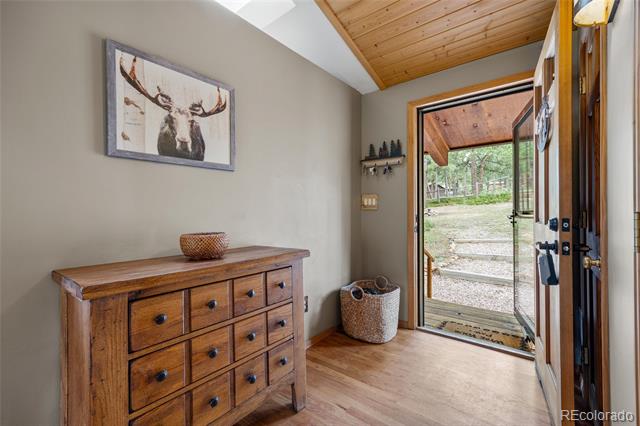 Entryway with a wooden dresser, framed deer artwork, and an open glass door to the yard.