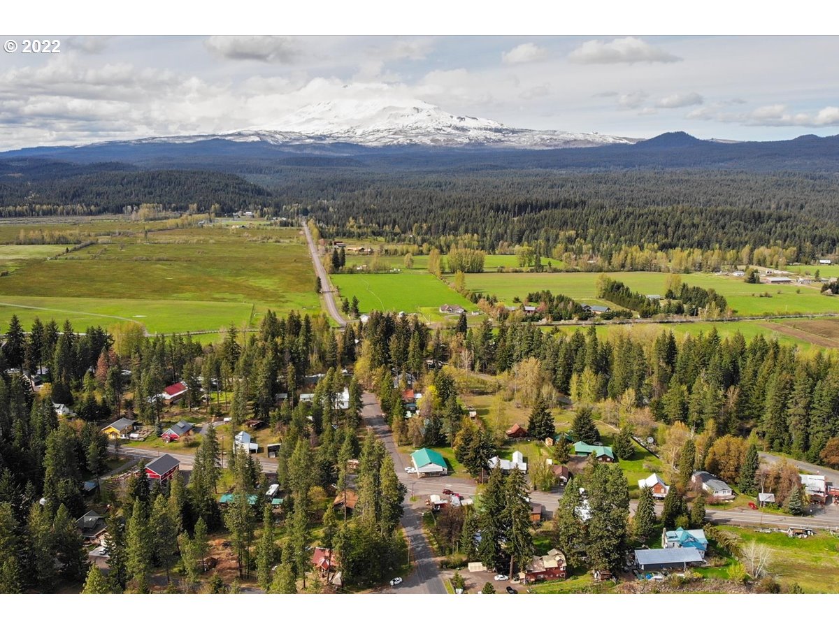 Aerial view of a rural neighborhood and fields with a snow-covered mountain in the distance.