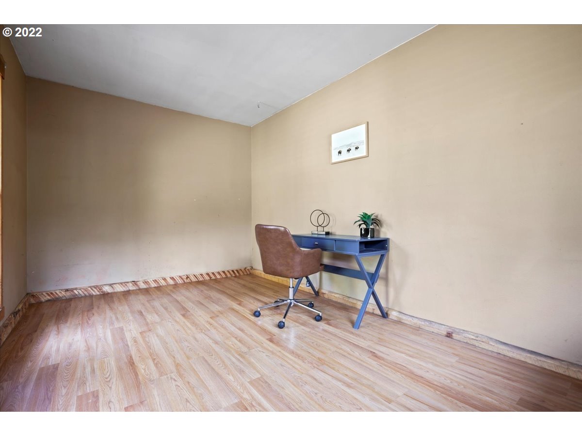 Mostly empty home office with a blue desk, brown swivel chair, and wood-look flooring.