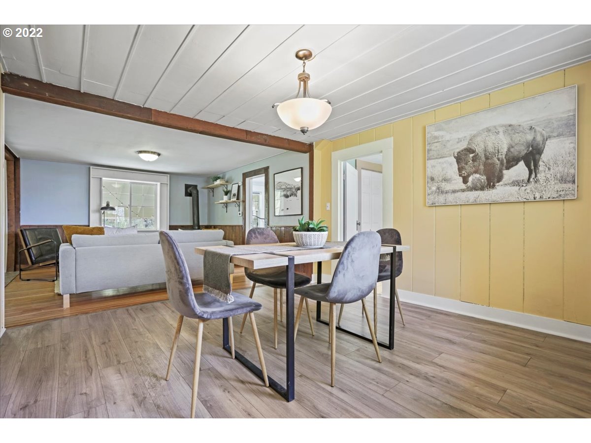 Dining and living area with yellow paneled walls, a wood-burning stove, and buffalo artwork.