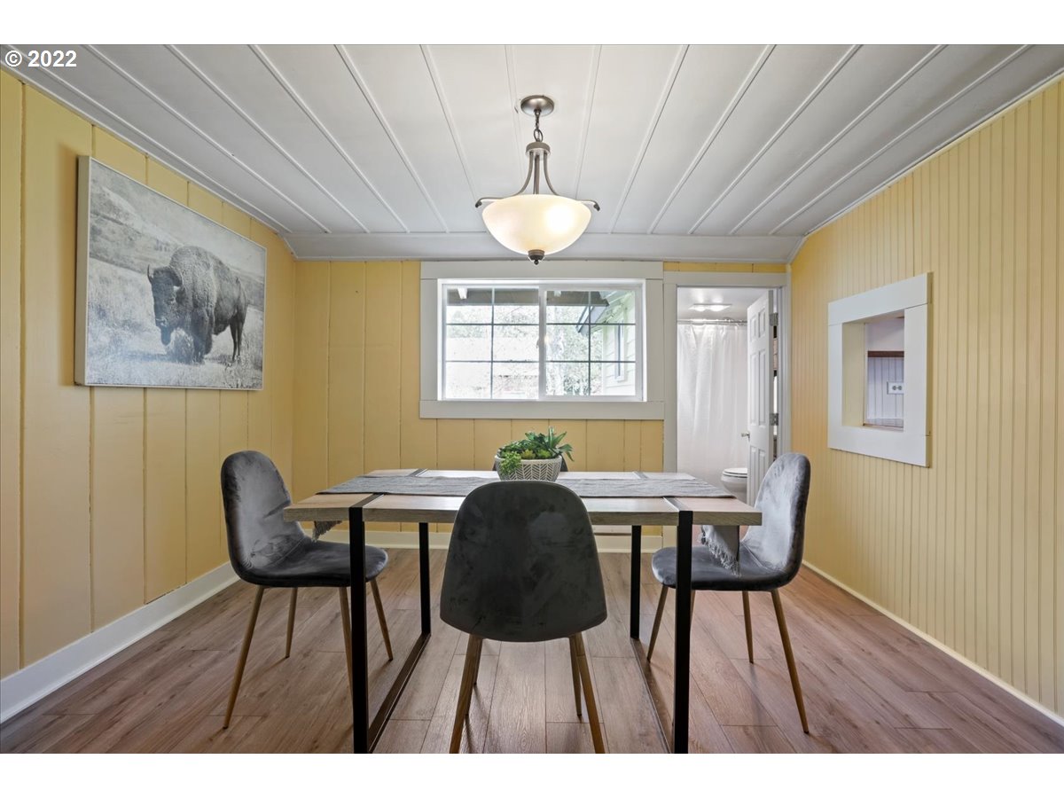 Dining room with yellow paneled walls, a dark table and chairs, and a framed buffalo print.