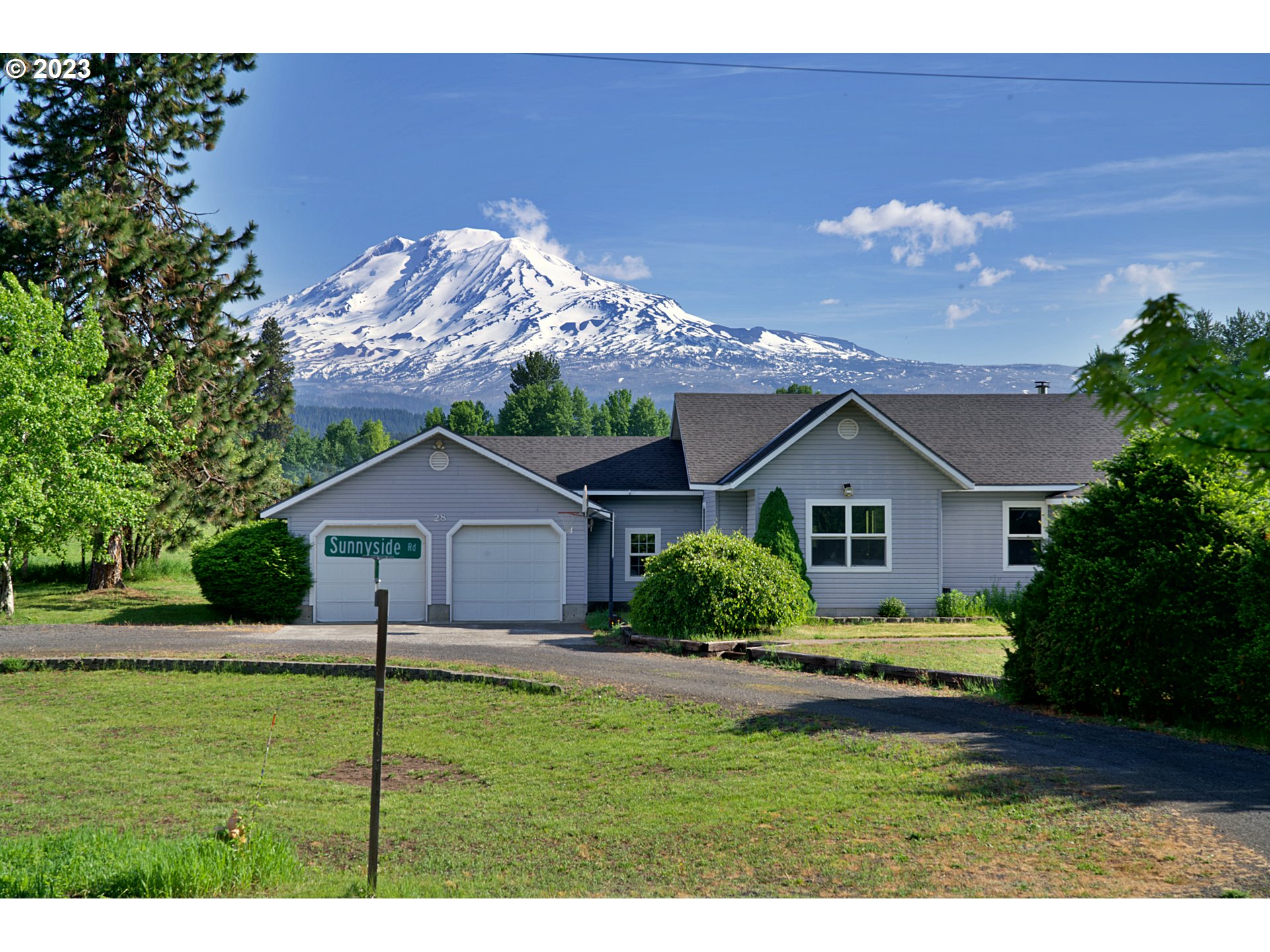 Gray home with two garage doors and a snowy Mount Adams rising behind it.
