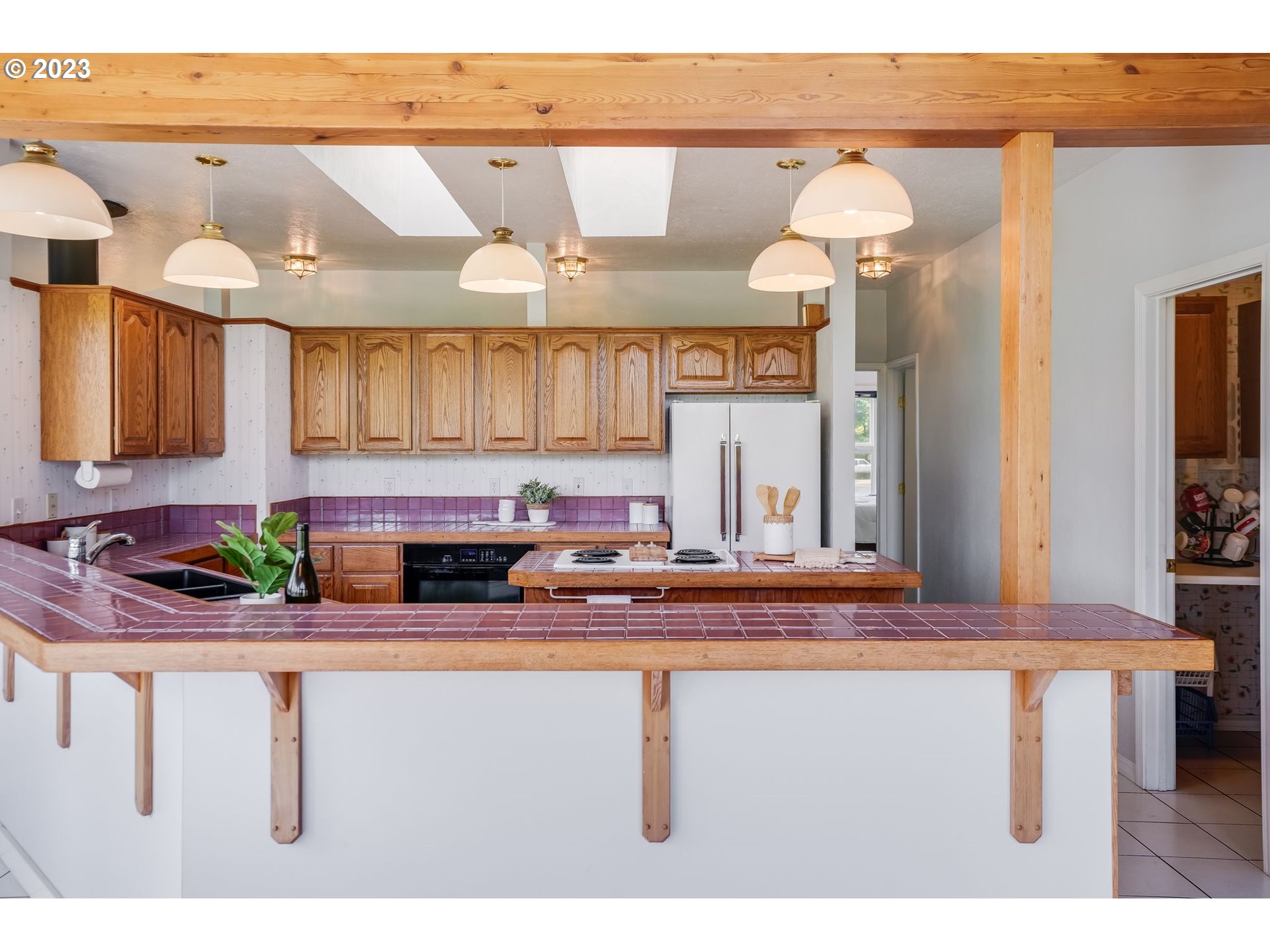 Kitchen with oak cabinets, purple tile counters, and a wide breakfast bar.