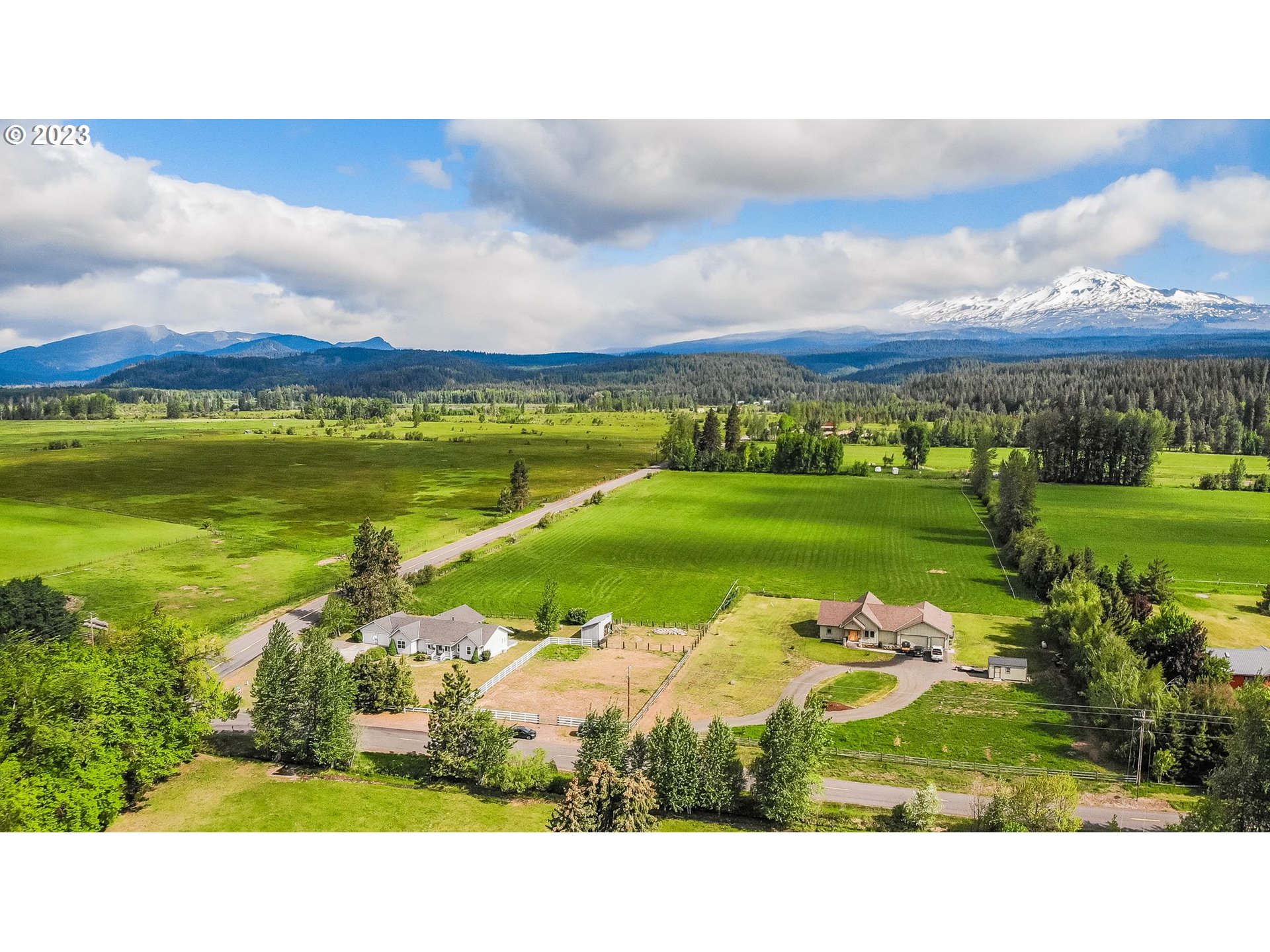 Aerial view of rural homes and fields with a snow-capped mountain in the distance.