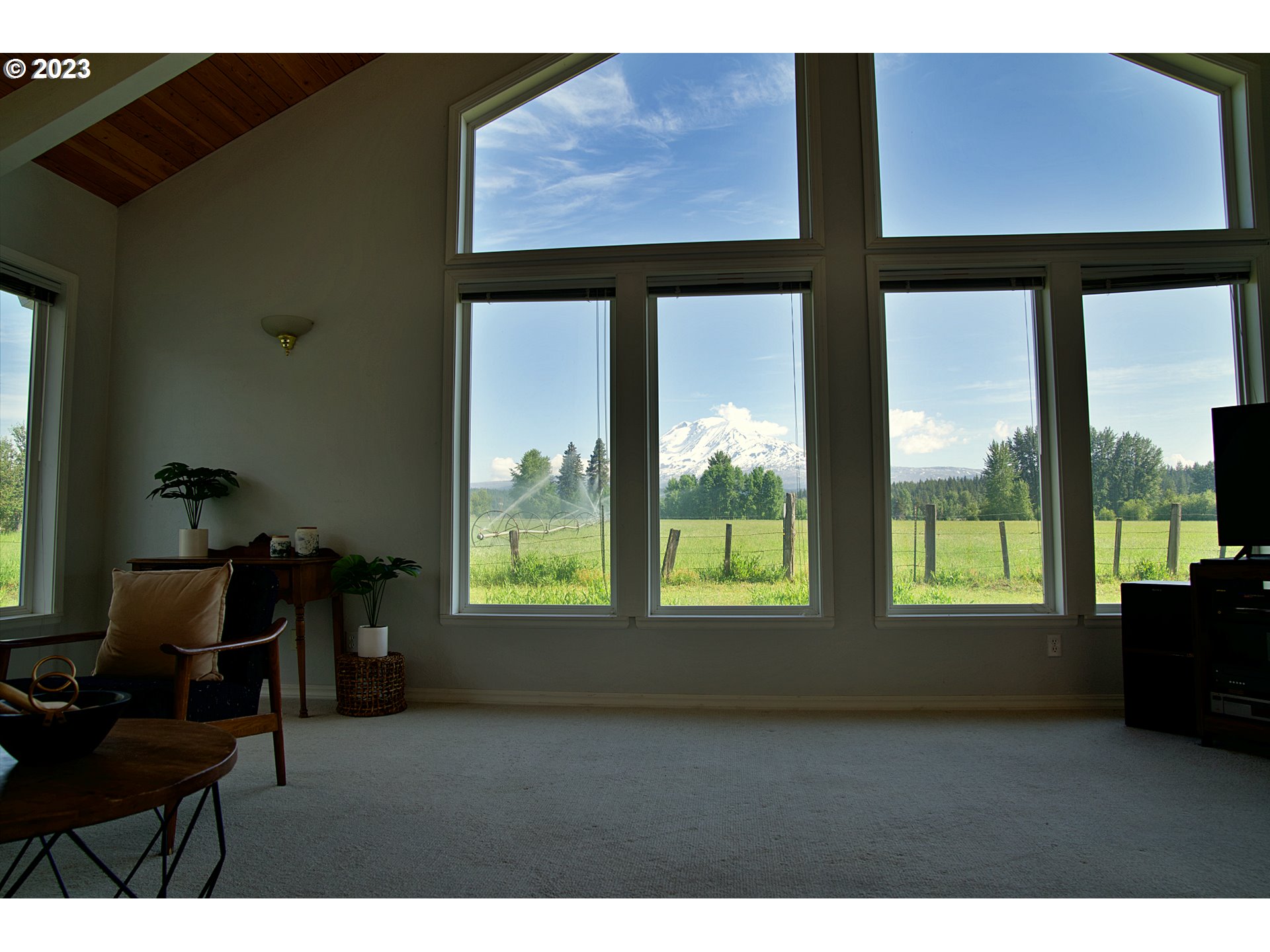 Living room with tall windows framing Mount Adams beyond a green field.