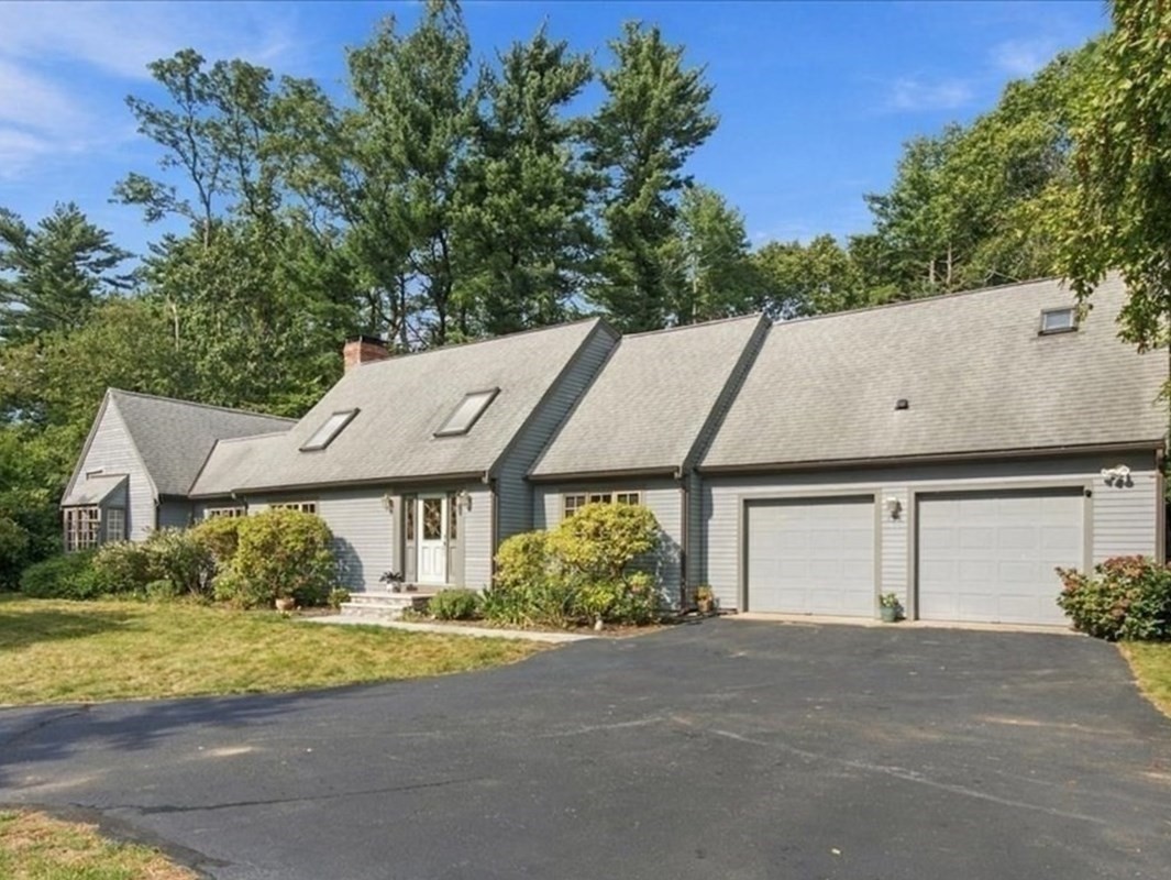 Gray single-story house with two garage doors, skylights, and a wide paved driveway.