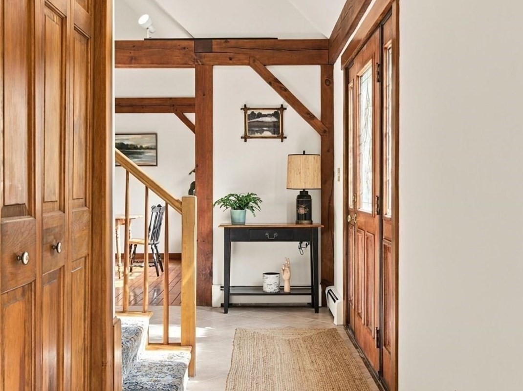 Entry hall with exposed timber beams, paneled wood doors, and a staircase.