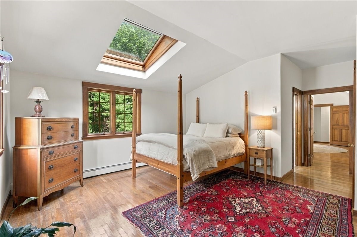 Bedroom with a four-poster bed, red patterned rug, and large skylight.