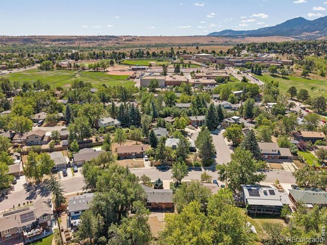 Aerial view of a leafy Boulder neighborhood with homes and mountains in the distance.