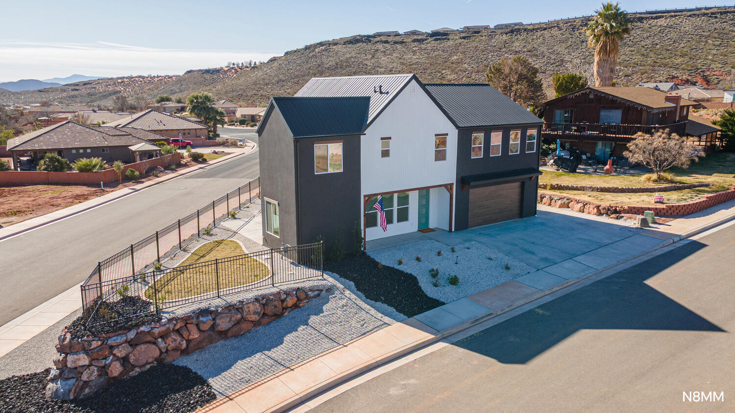 Modern two-story home with a metal roof, attached garage, and gravel landscaping.