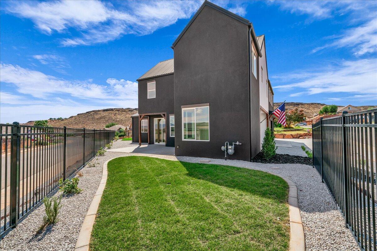 Modern two-story home beside a curved lawn, gravel landscaping, and black metal fences.