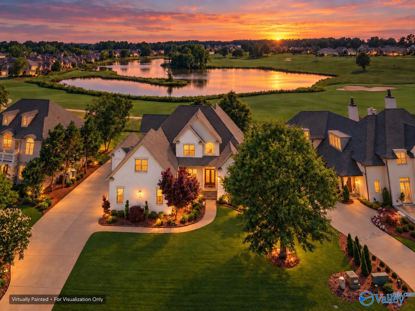 Aerial view of homes beside a golf course and ponds glowing at sunset.