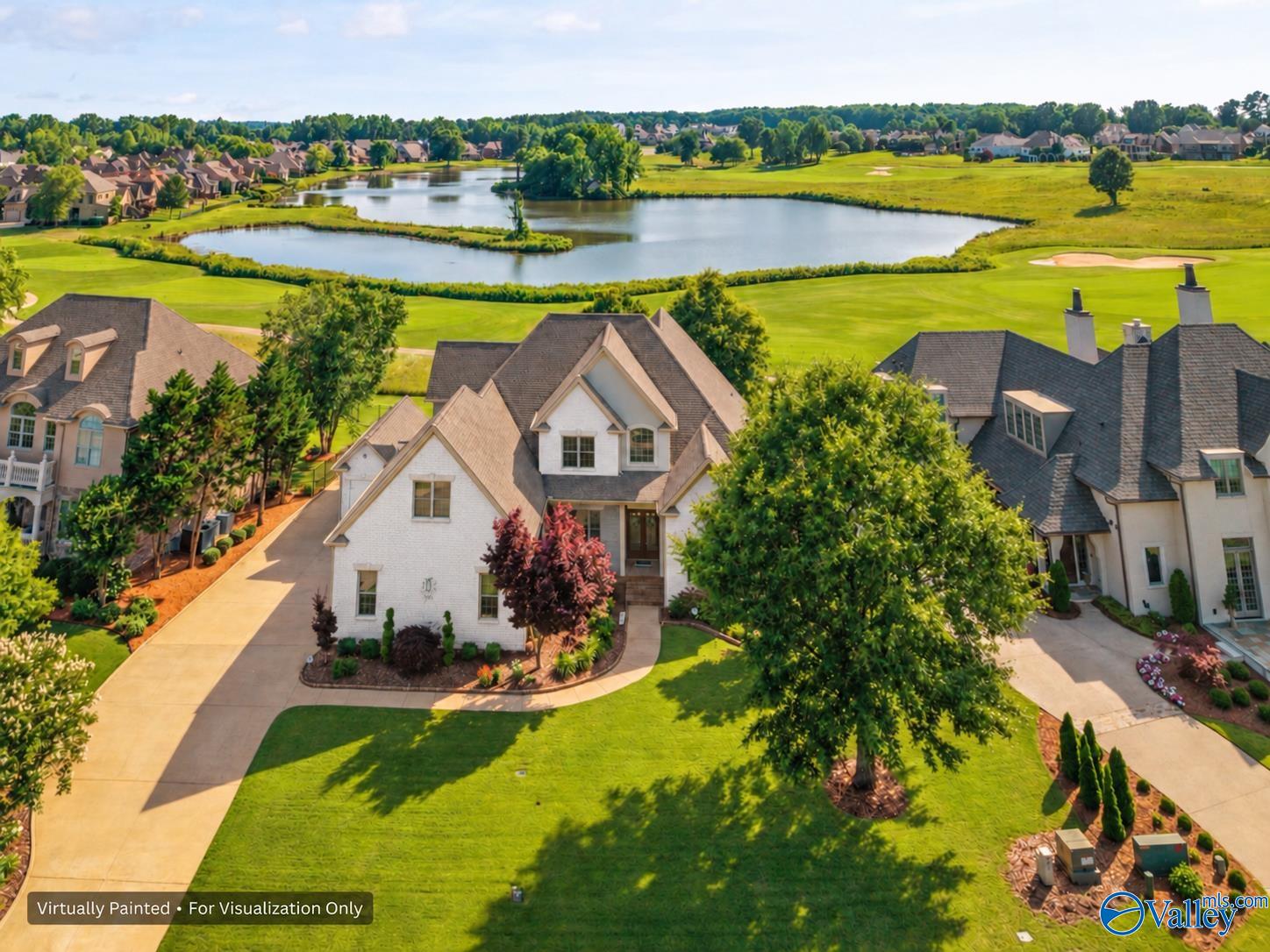 Aerial view of a house beside a pond and golf course in a landscaped neighborhood.