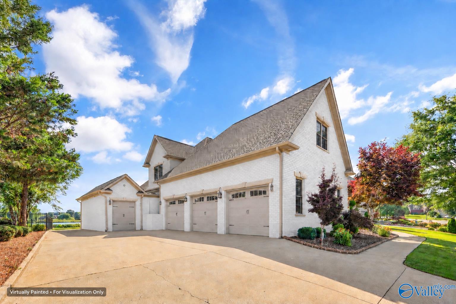White-brick house with three garage doors and a wide driveway, shown with landscaped grounds.