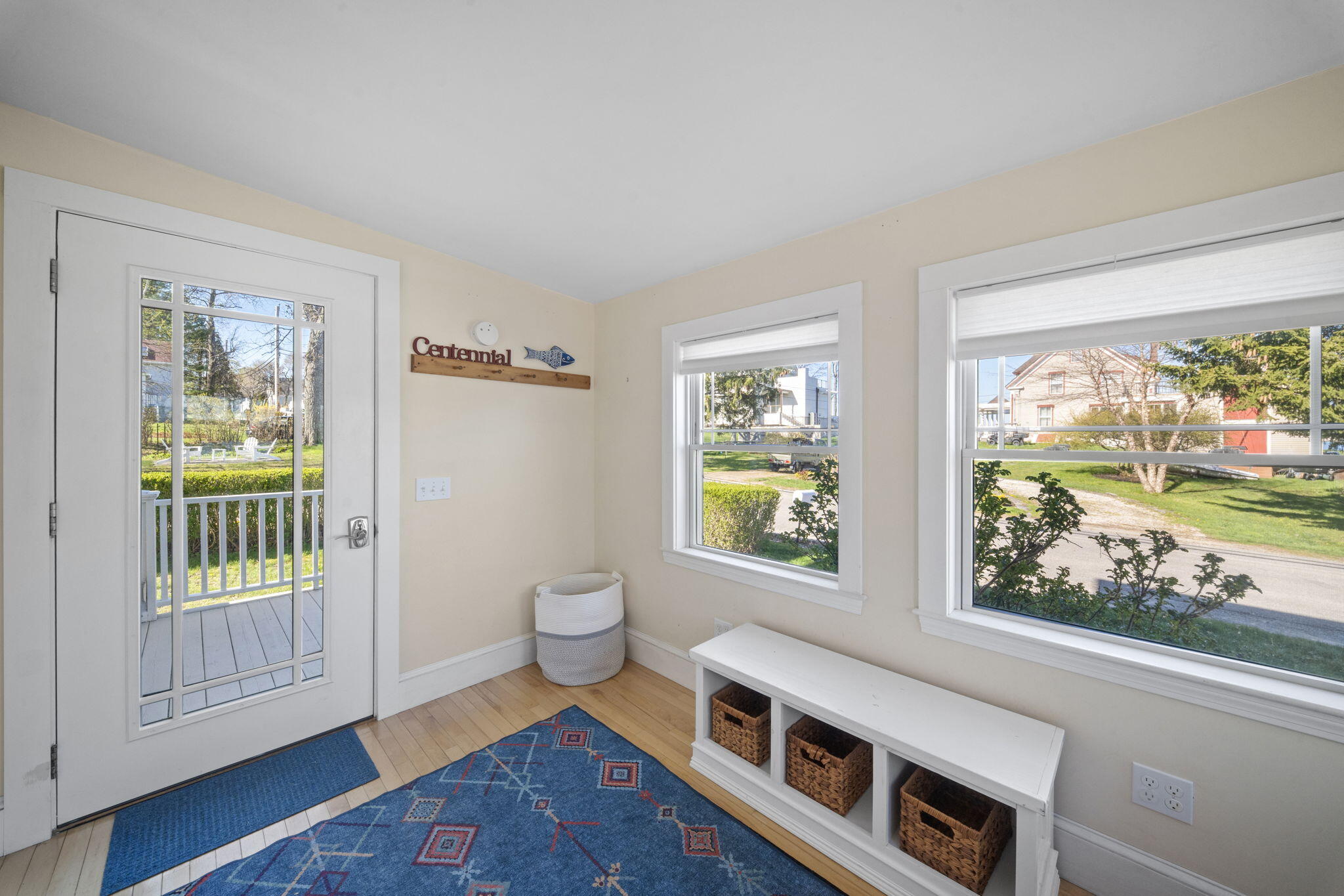 Entryway with a glass-paneled door, two large windows, and a built-in bench with baskets.