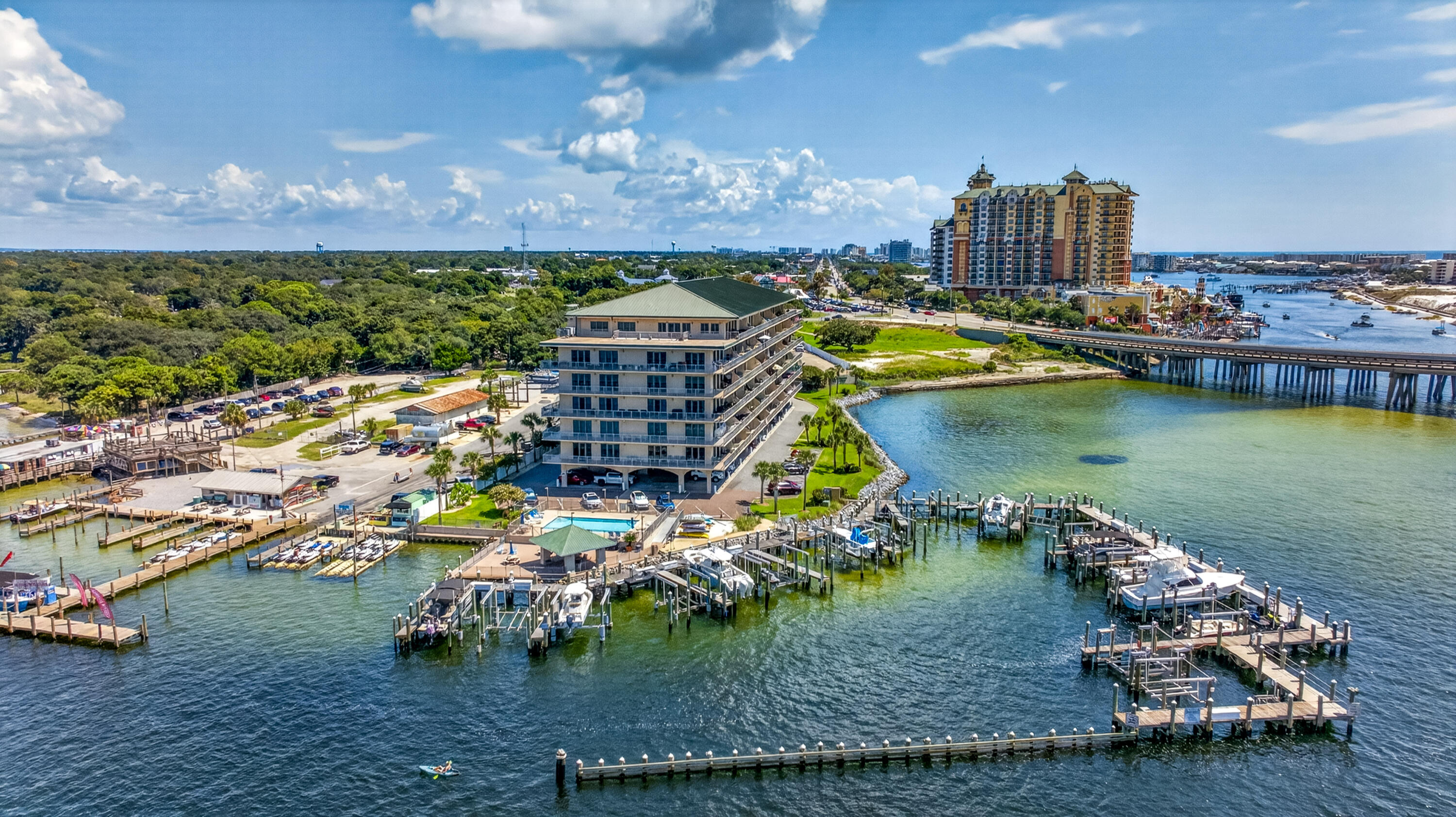 Waterfront condominium beside Destin Harbor, with marina docks, boats, and a bridge.