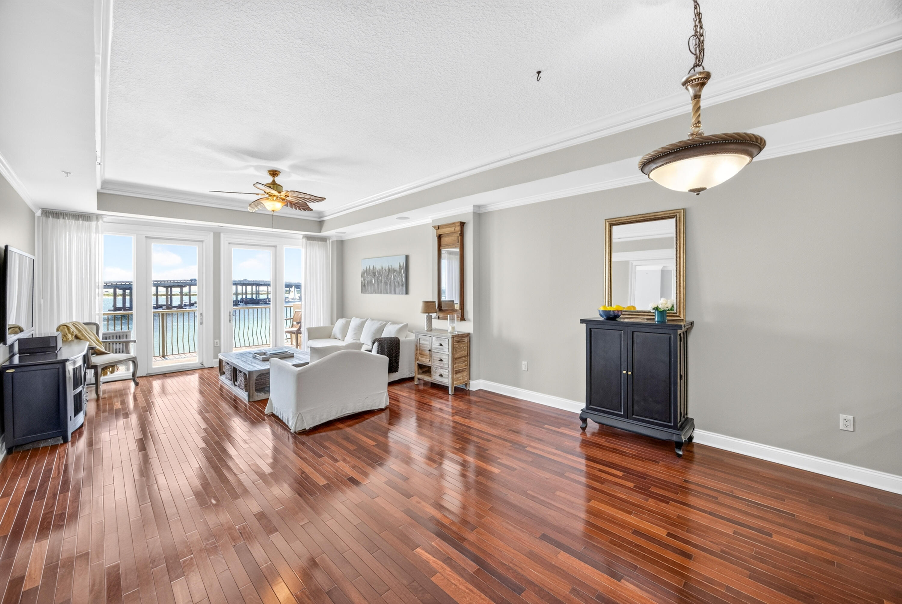 Living room with polished hardwood floors and water views through tall windows.