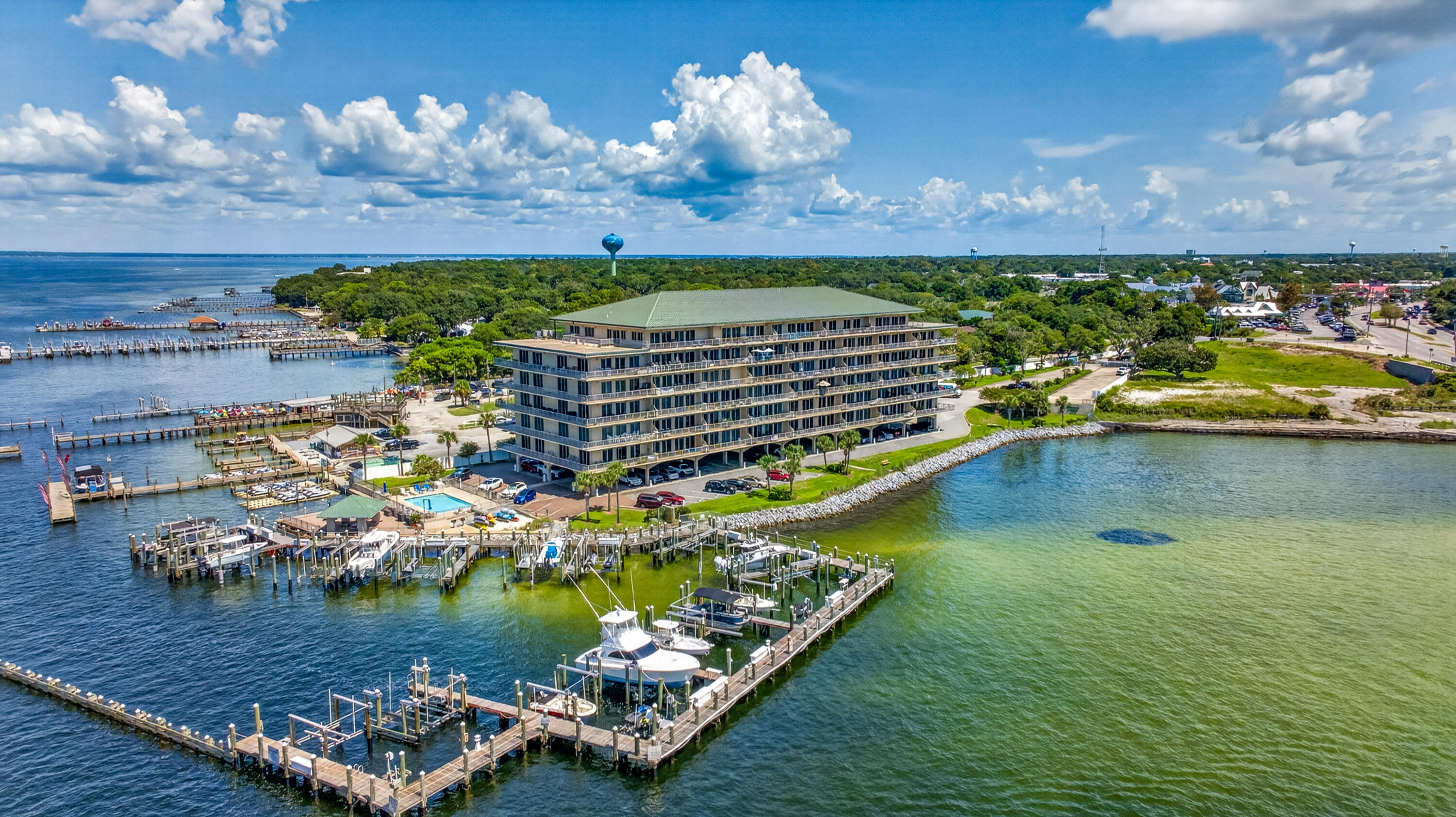 Waterfront condominium and marina with boat docks, boats, and a pool beside open water.