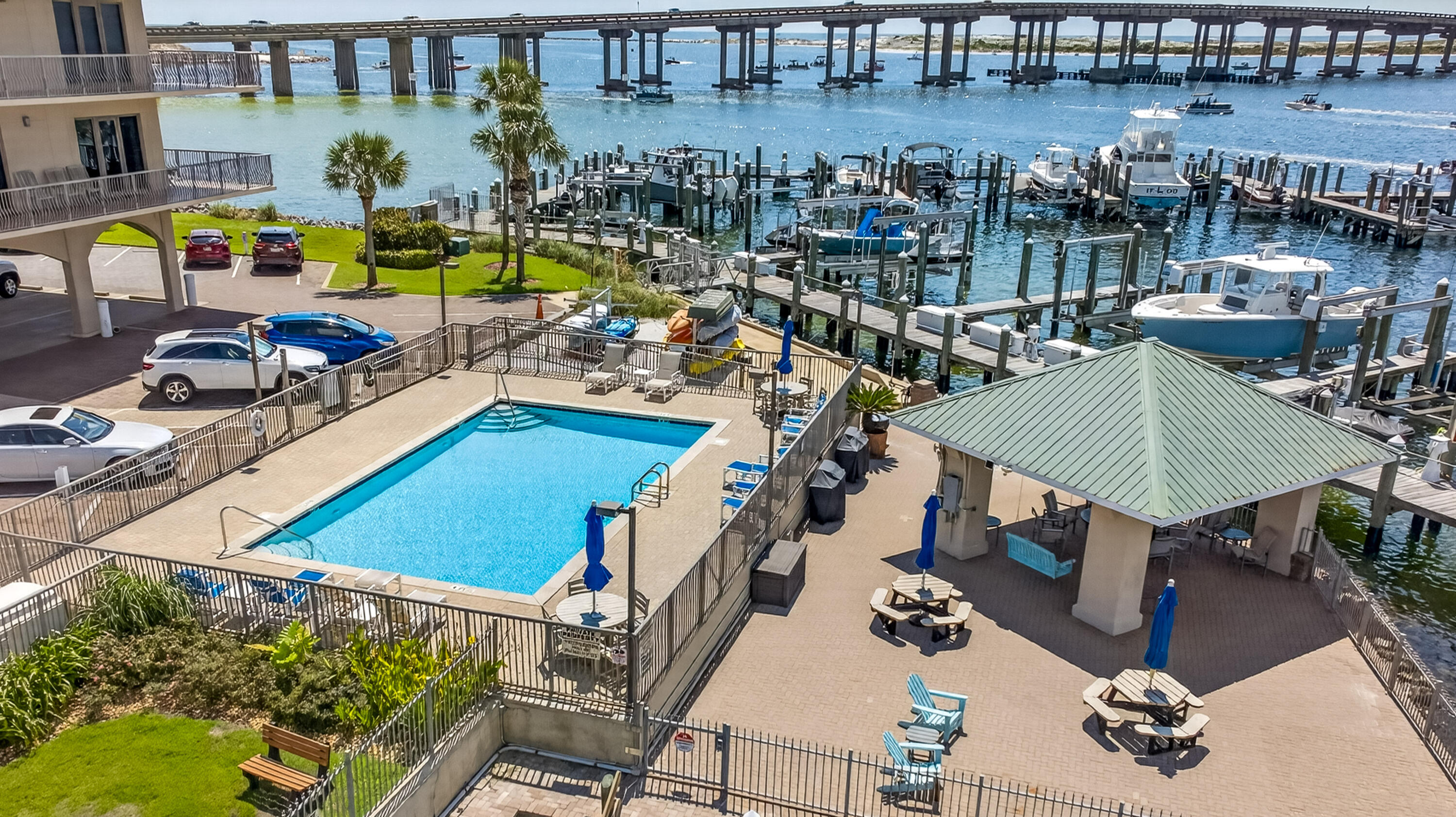 Waterfront pool and marina with boats and a bridge in the background.