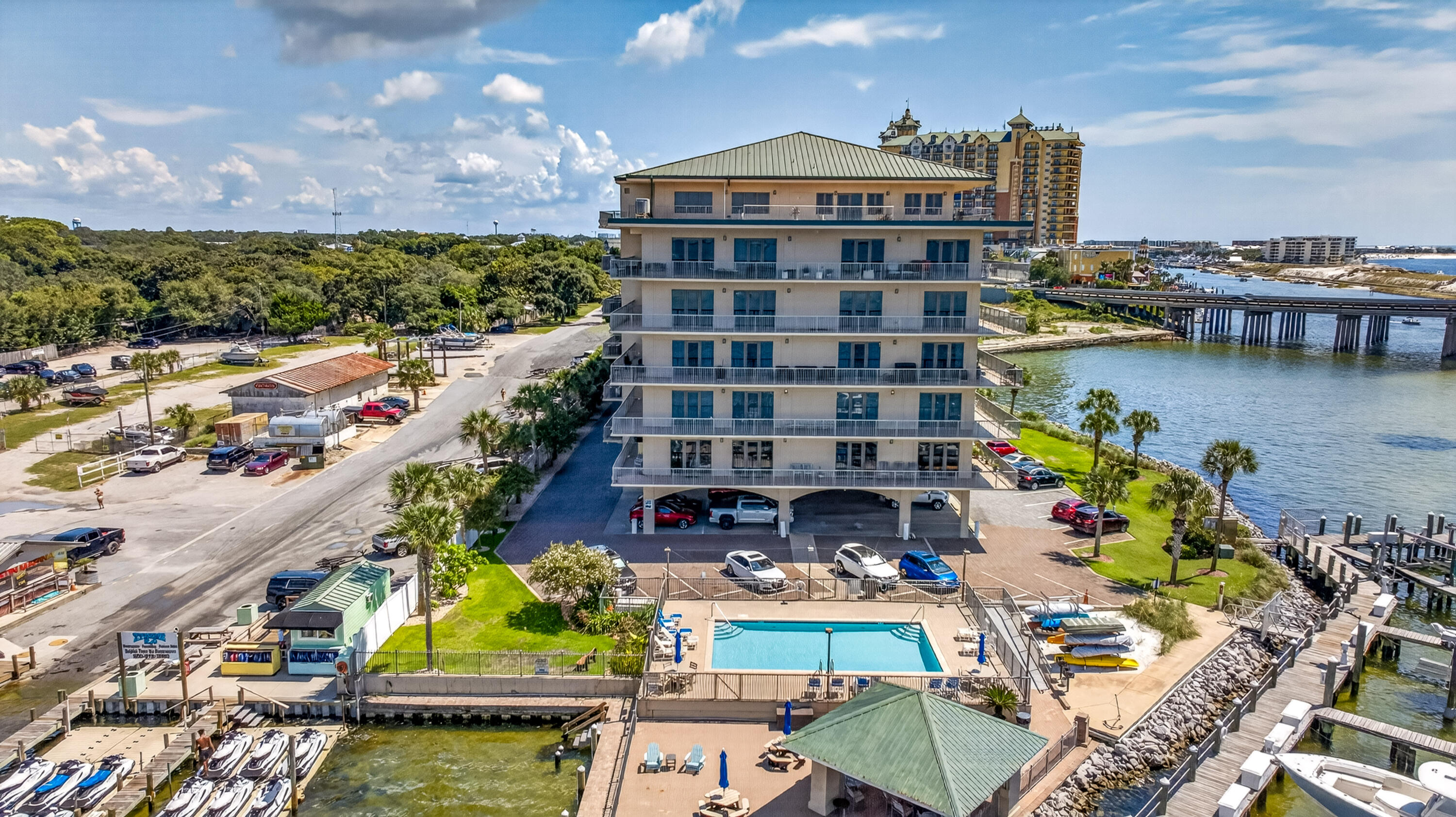 Waterfront condominium with balconies, pool, boat docks, and a bridge over the water.