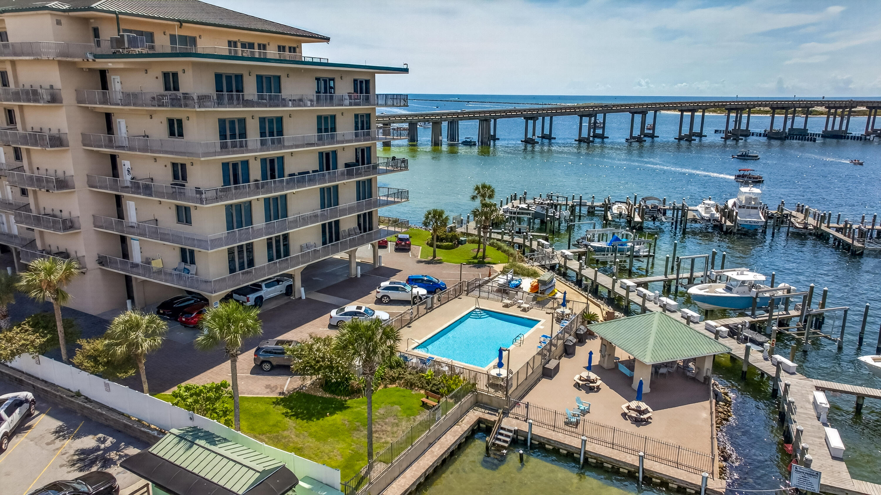 Waterfront condominium with a pool and marina beside a bridge.