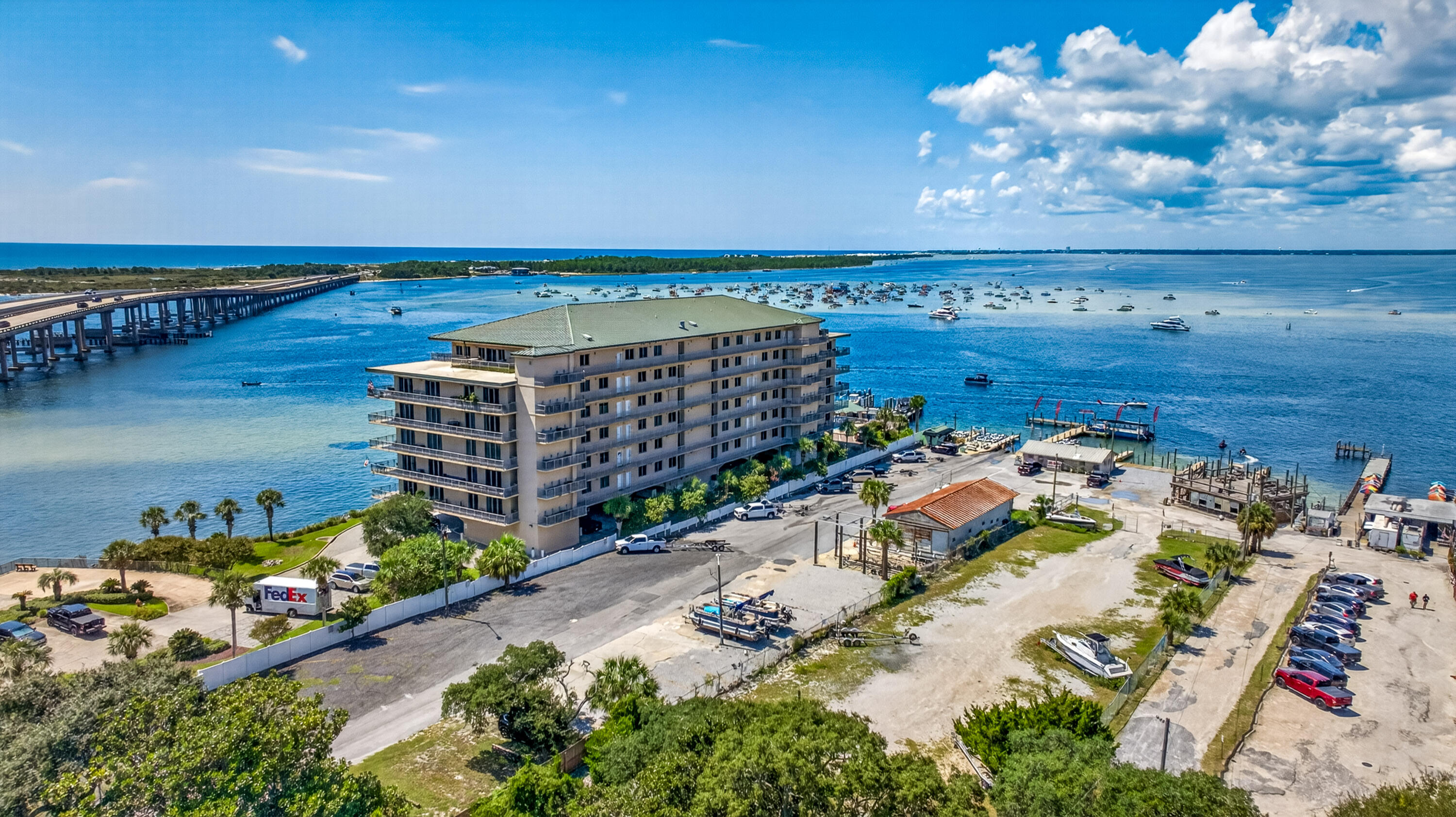 Waterfront condominium beside a marina, with boats across the bay and a bridge in the distance.