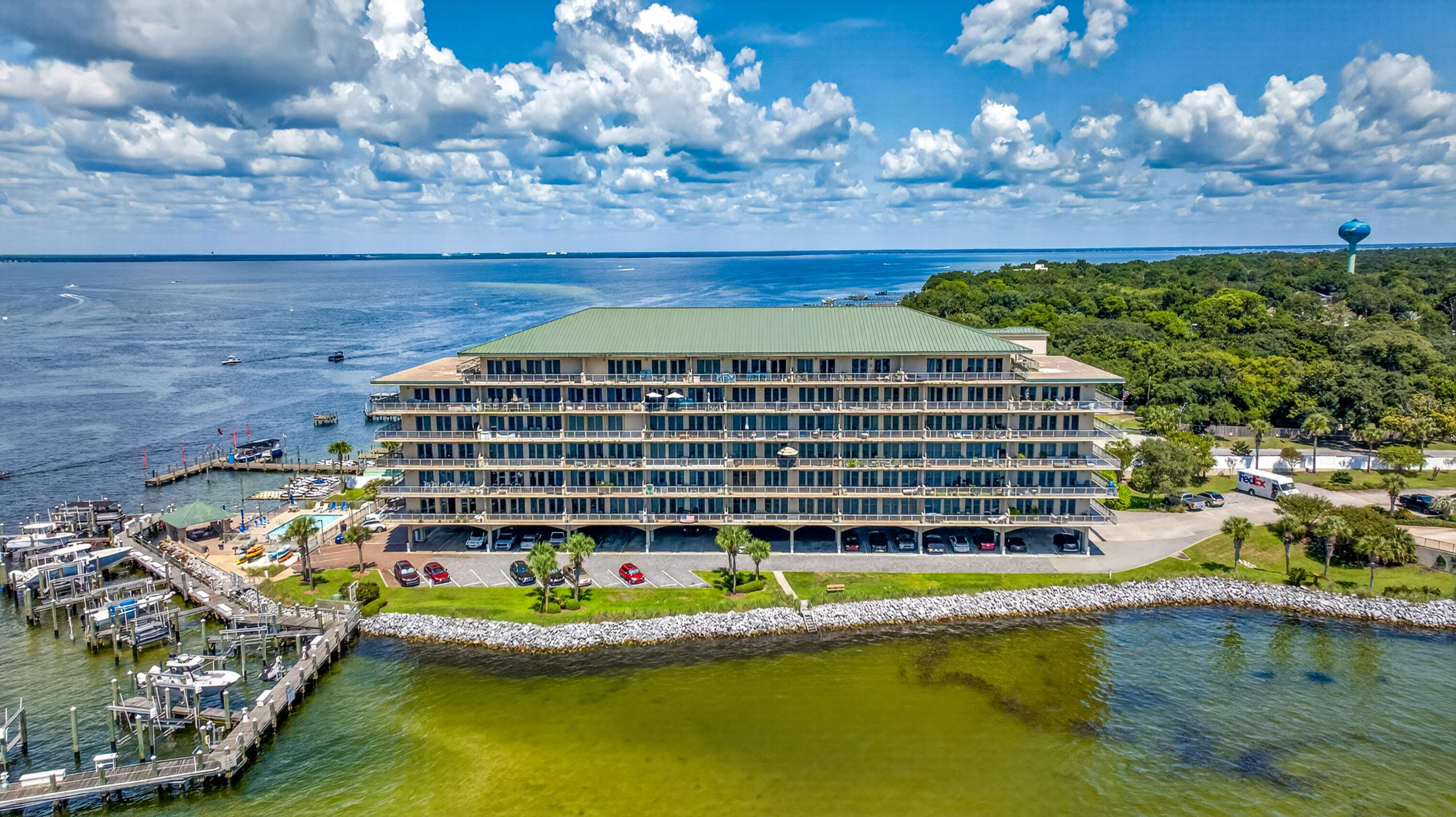 Waterfront condominium with rows of balconies, boat docks, and a broad view across the water.