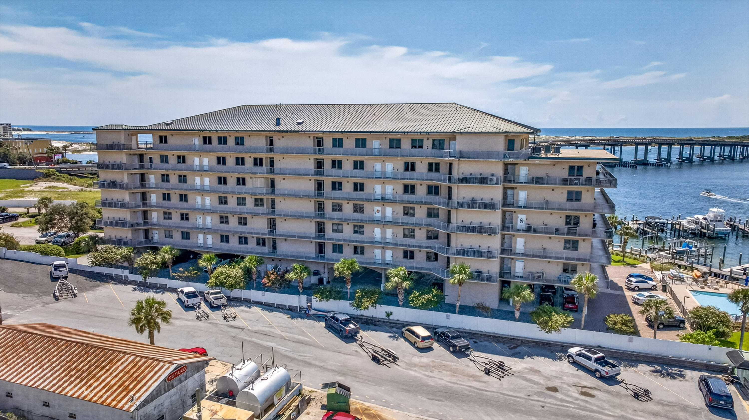 Multi-story waterfront condominium with long balconies, a marina, and a pool.