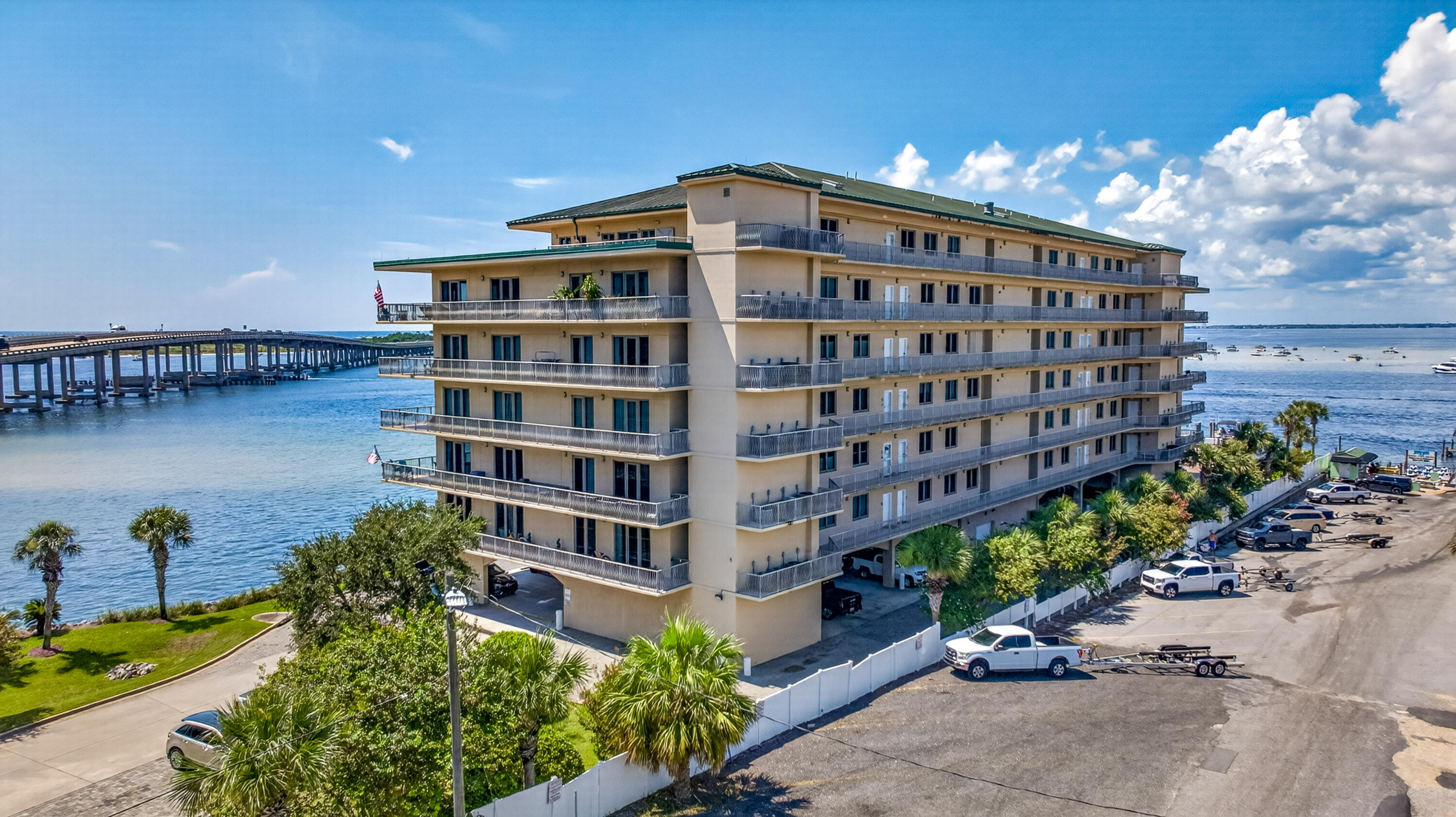 Waterfront condominium with long balconies, a bridge, and boats on the bay.
