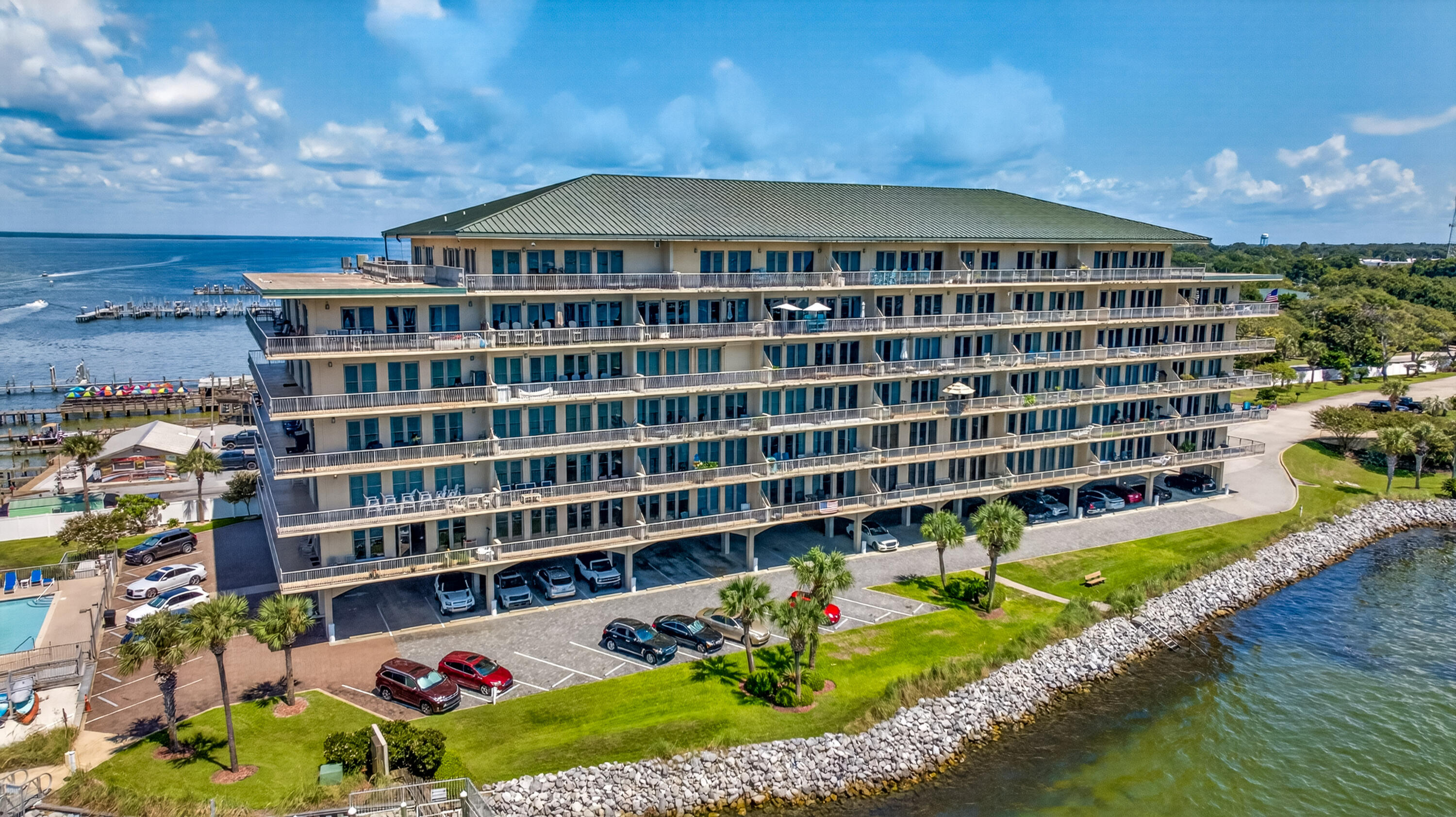 Waterfront condominium with long balconies and a rocky shoreline beside the water.