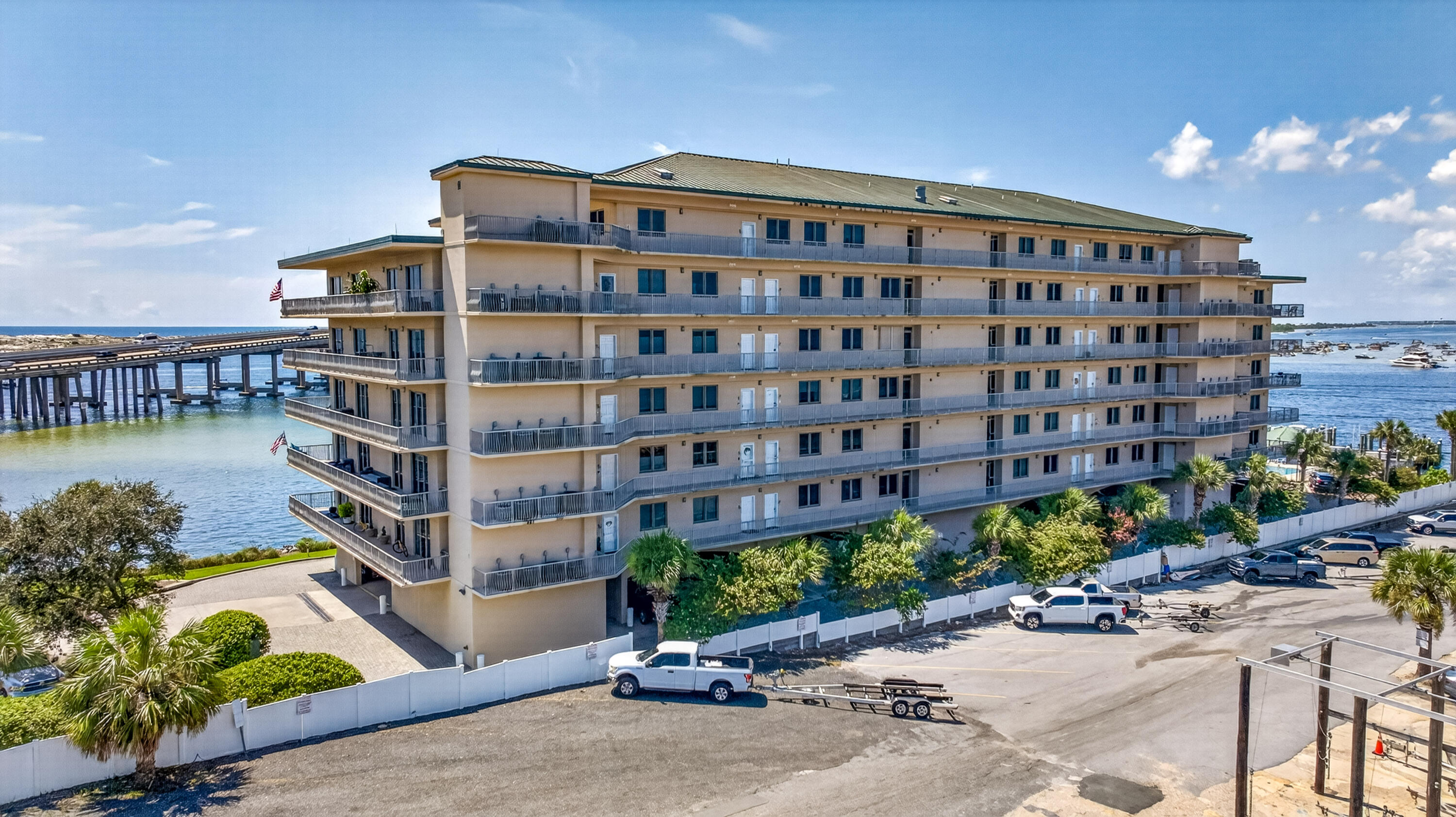 Waterfront condominium with rows of balconies beside a pier and marina water.