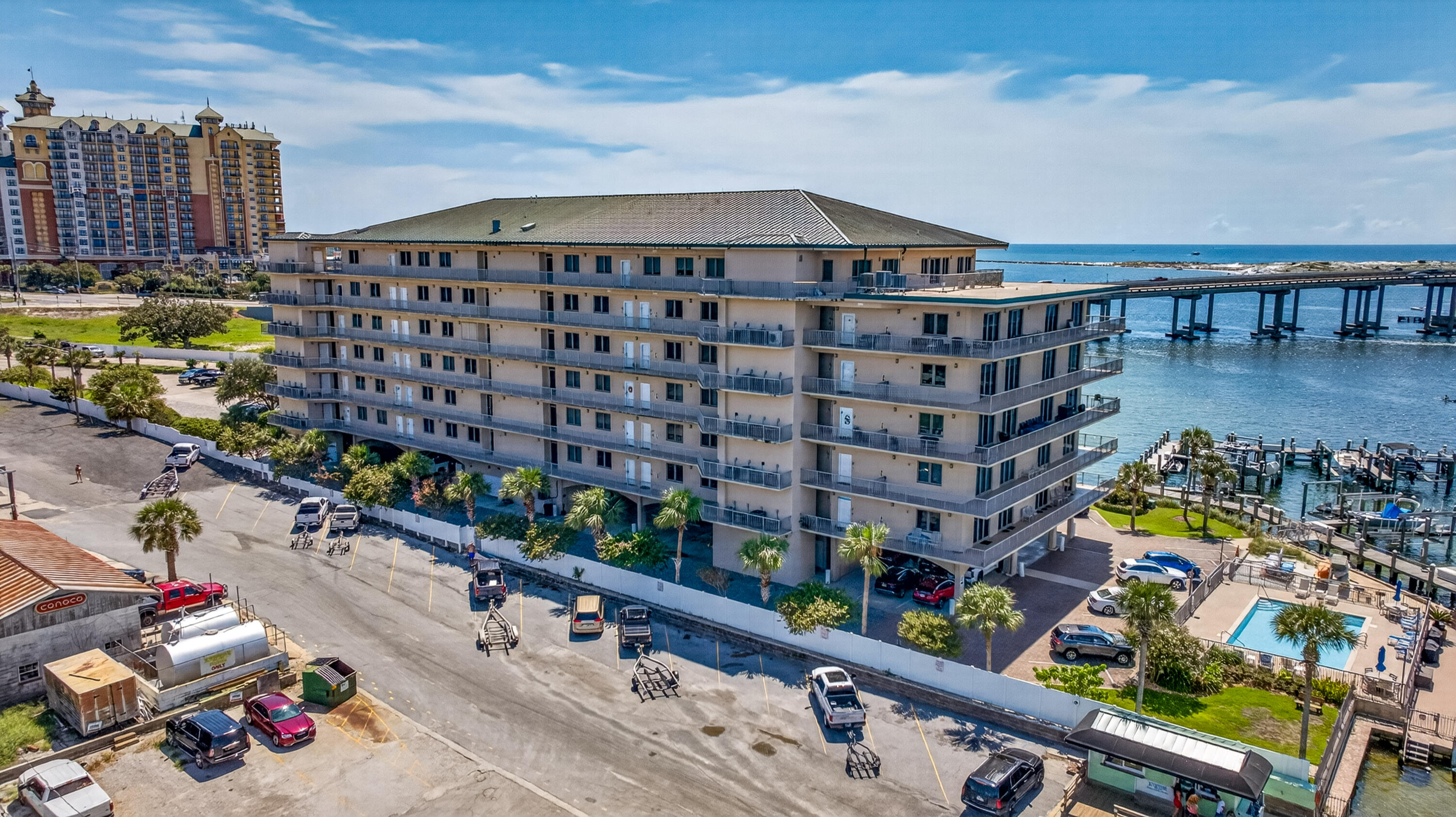 Waterfront condominium with balconies, pool, and marina beside a bridge.