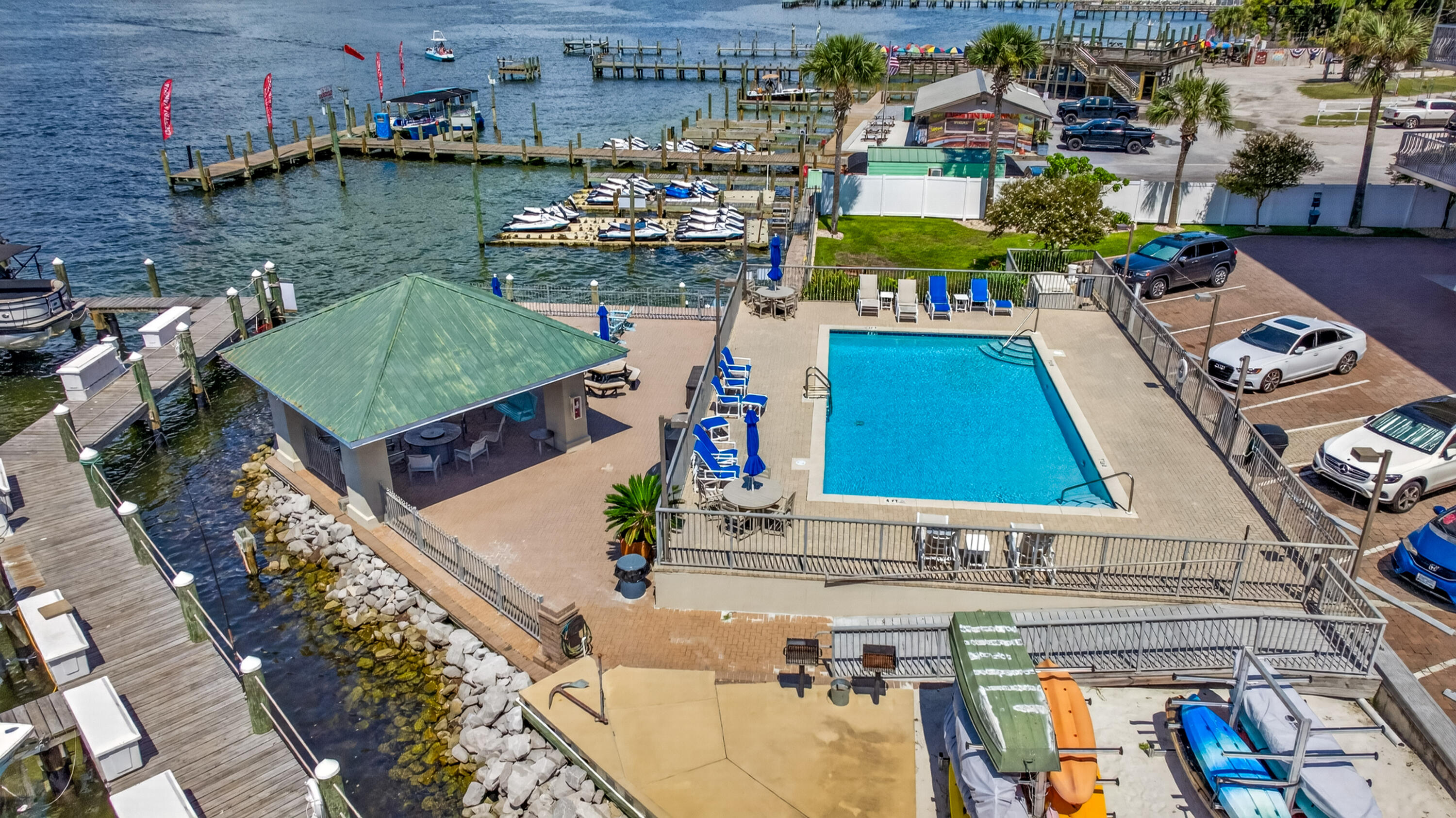 Waterfront pool and pavilion beside marina docks and boats.