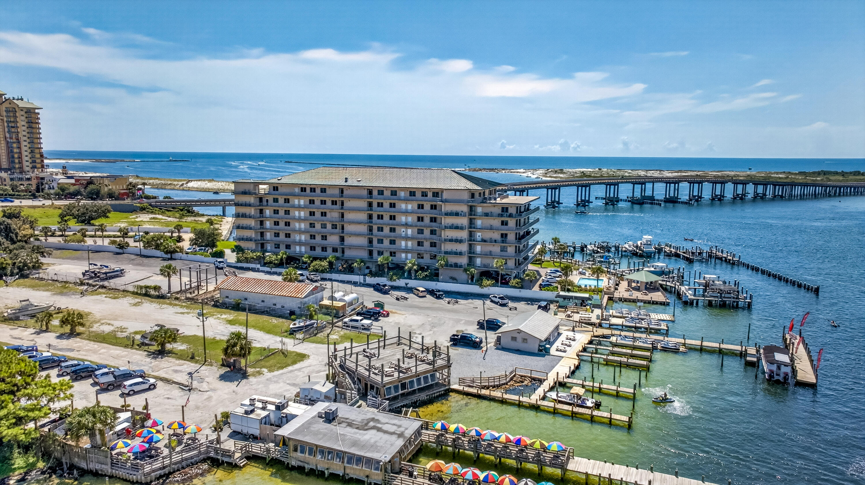 Waterfront condominium beside a marina, with docks, a bridge, and the Gulf beyond.