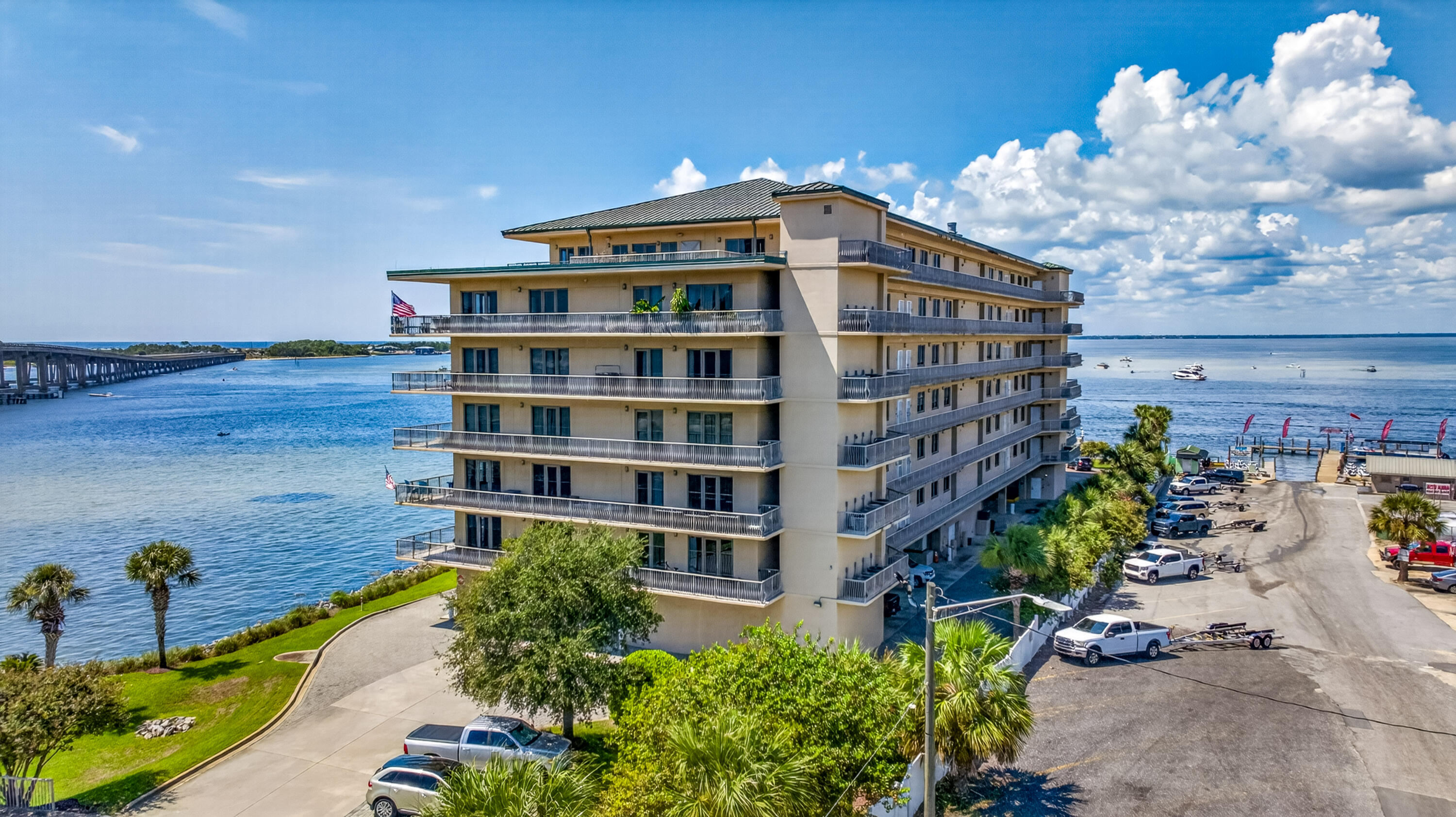 Waterfront condominium with long balconies beside blue water and a pier.