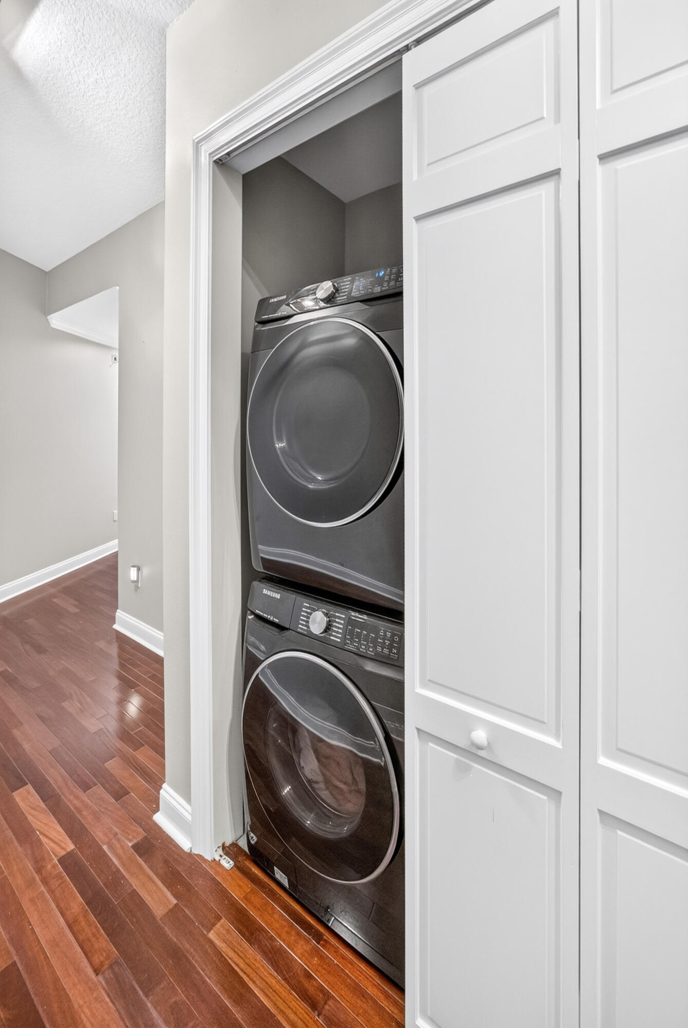 Stacked Samsung washer and dryer tucked into a white paneled laundry closet.