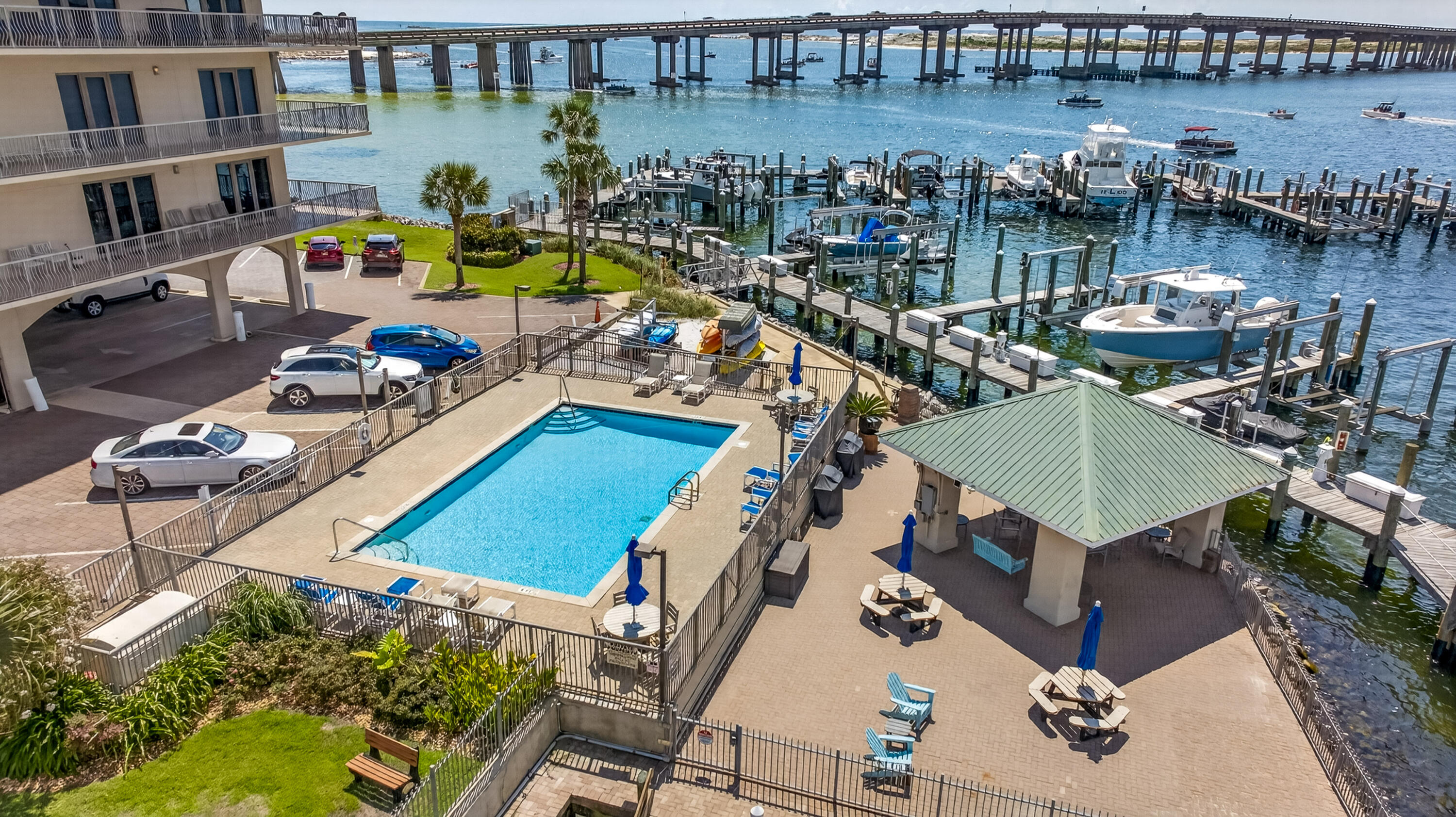 Waterfront condominium pool and marina, with boats and a bridge across the water.