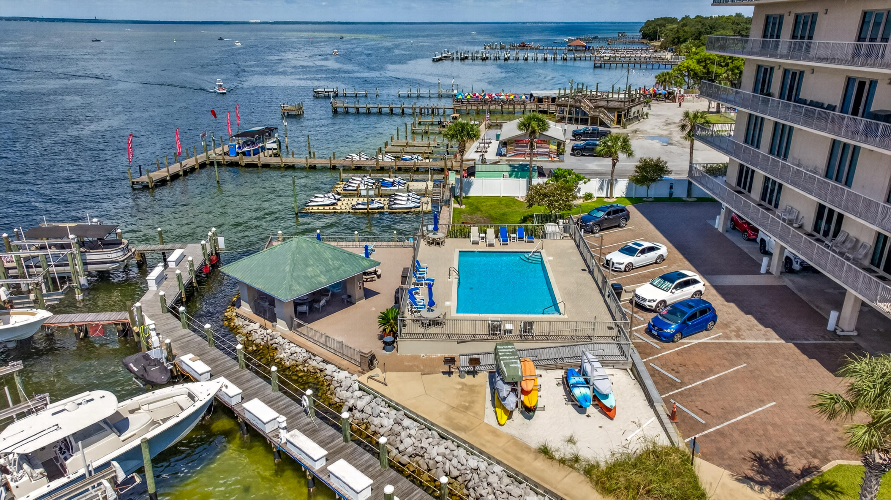 Waterfront condominium with a pool and marina docks lined with boats along the bay.
