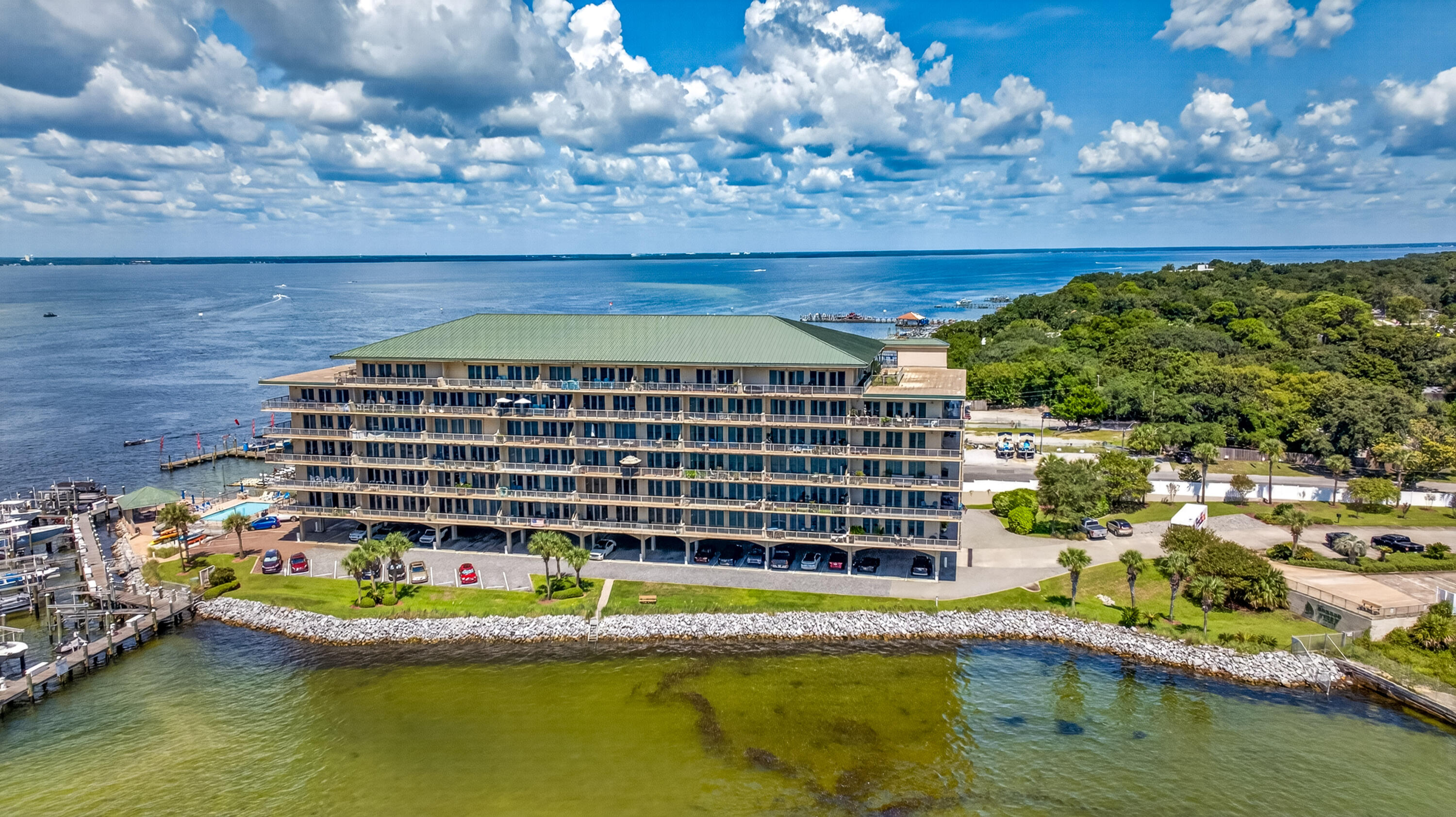 Waterfront condominium beside a marina, with balconies, a green roof, and expansive bay views.