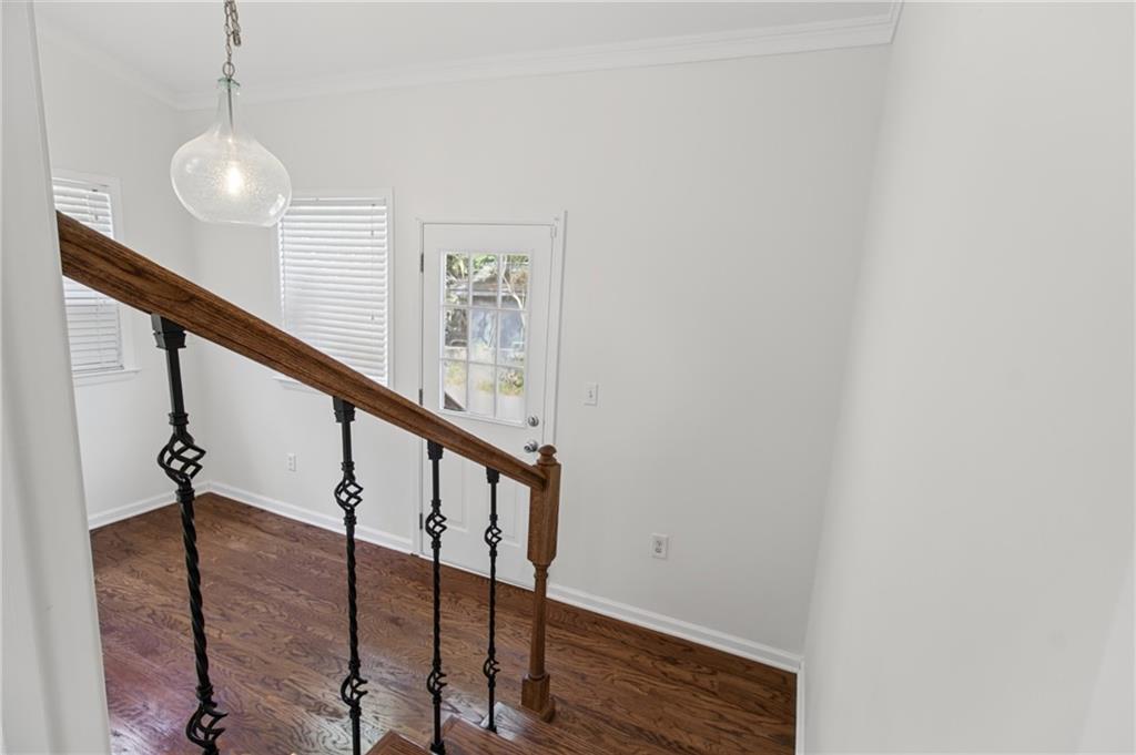 Entry hall with hardwood floors, an iron-baluster staircase, and a glass-paneled door.