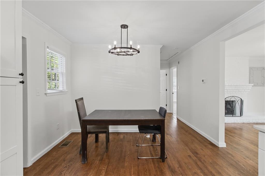 Dining room with a dark wood table, hardwood floors, and a view of an adjoining white brick fireplace.