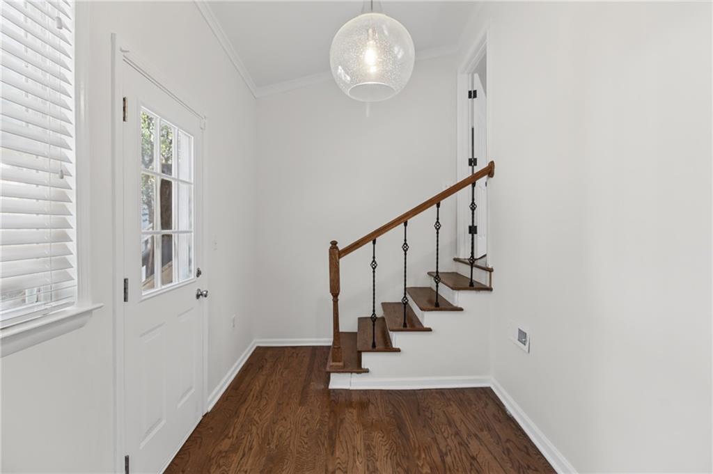 Entryway with dark hardwood floors, a glass-paneled door, and a short staircase with iron balusters.