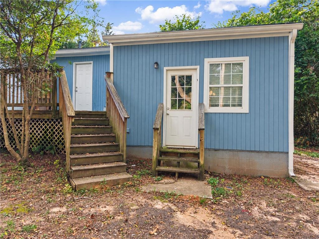 Blue-sided house exterior with two entry doors, wooden stairs, and a small raised deck.
