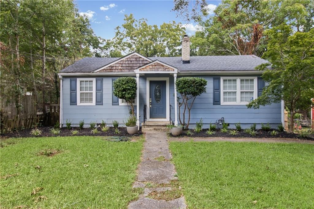 Blue single-story house with dark shutters and a stone walkway through the front lawn