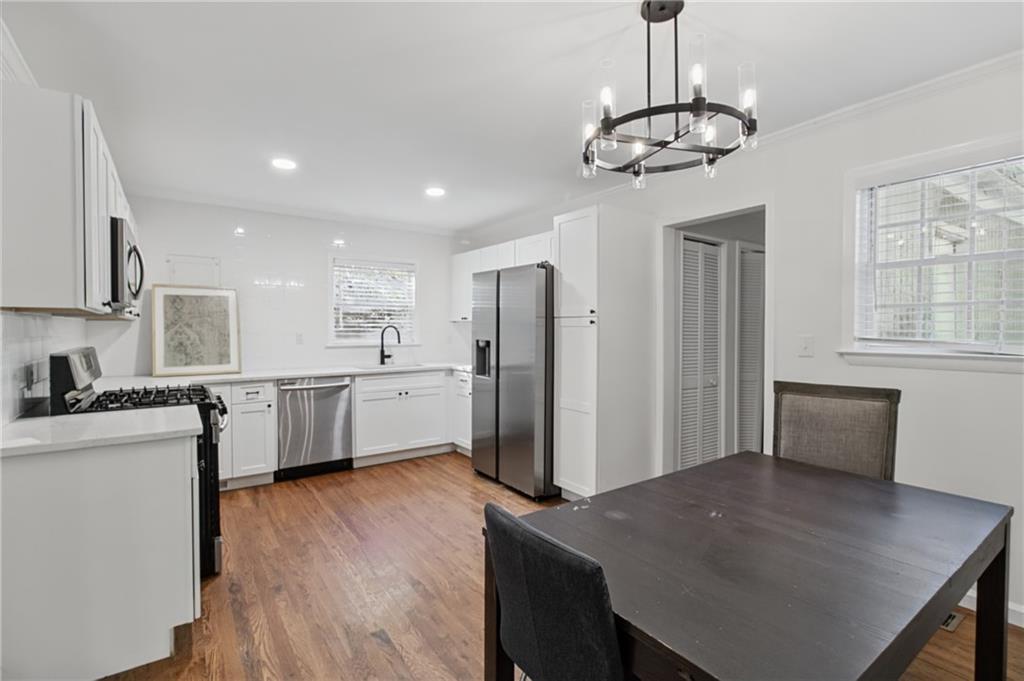 Kitchen and dining area with white cabinets, stainless steel appliances, and a dark wood table.
