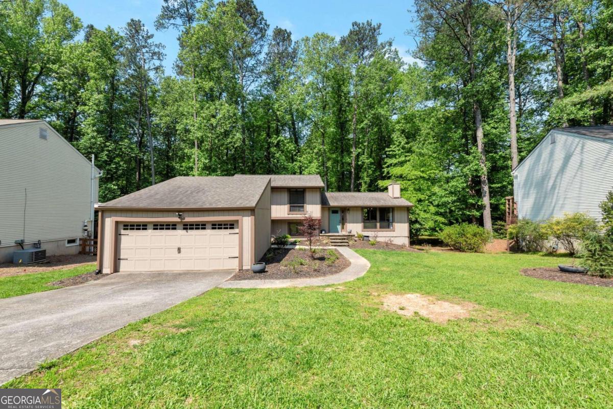 Home with a two-car garage and curved front walkway, set among mature trees.