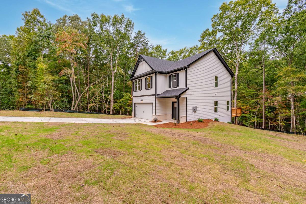 Two-story house with dark trim and attached garage on a wooded lot.
