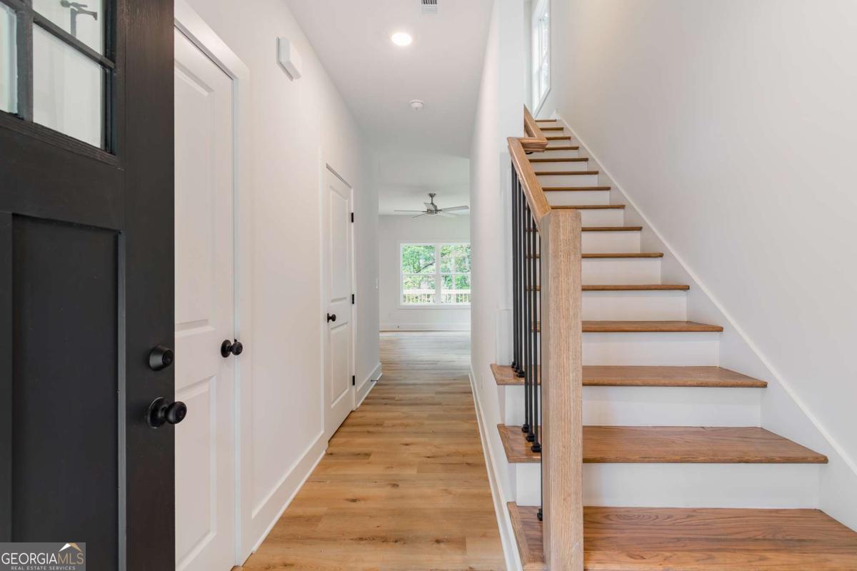Entry hallway with light wood floors and a staircase beside a black front door.