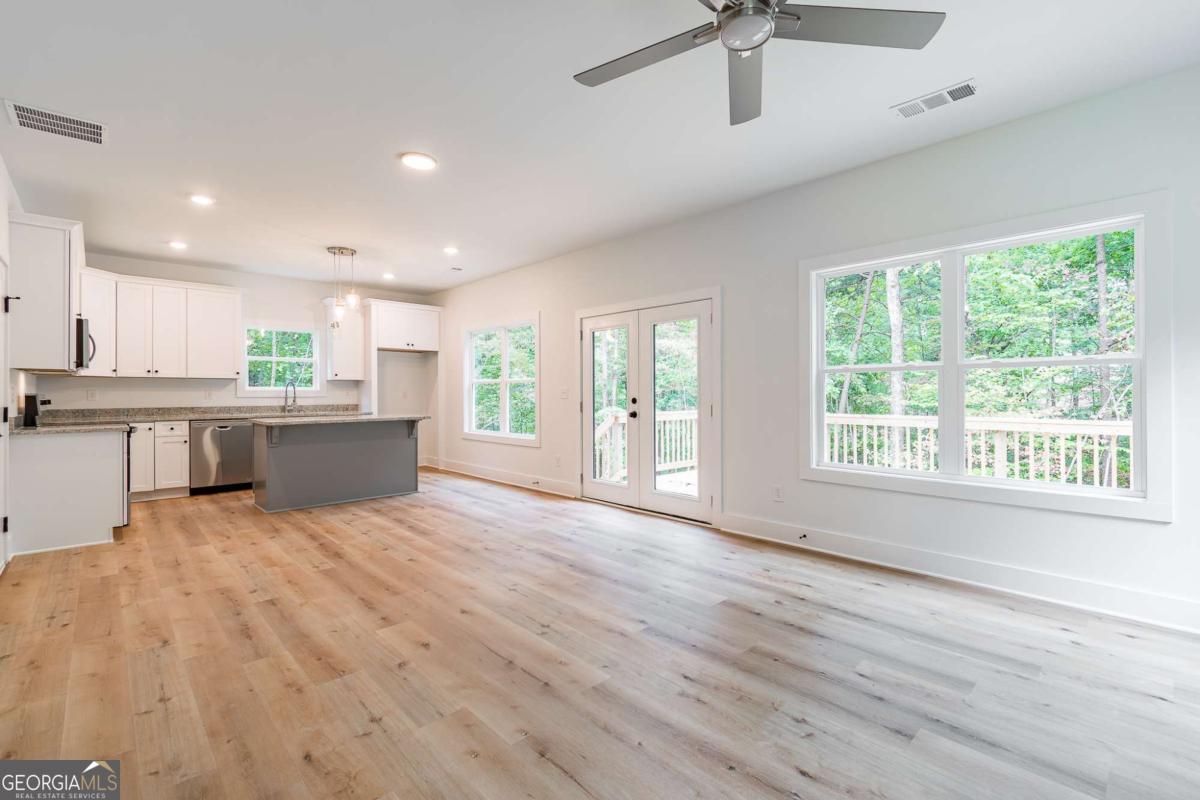 Vacant open-plan kitchen and living area with a gray peninsula and wooded views through large windows.